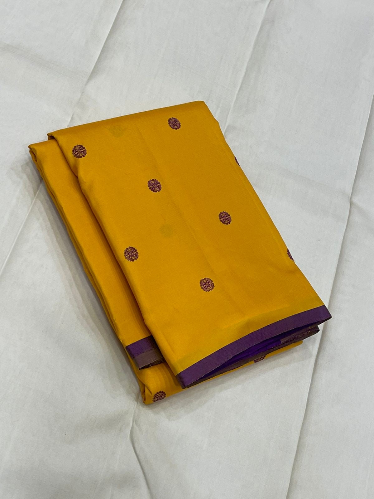 Manjal Vadamalli Chakram – Pure Kanchipuram Silk Saree
Marigold yellow body with purple floral thread buttas
Grand royal purple pallu with gold medallion zari & reku-style stripes
Handwoven Double Warp Weave | Silk Mark Certified | Fall & Pico Done