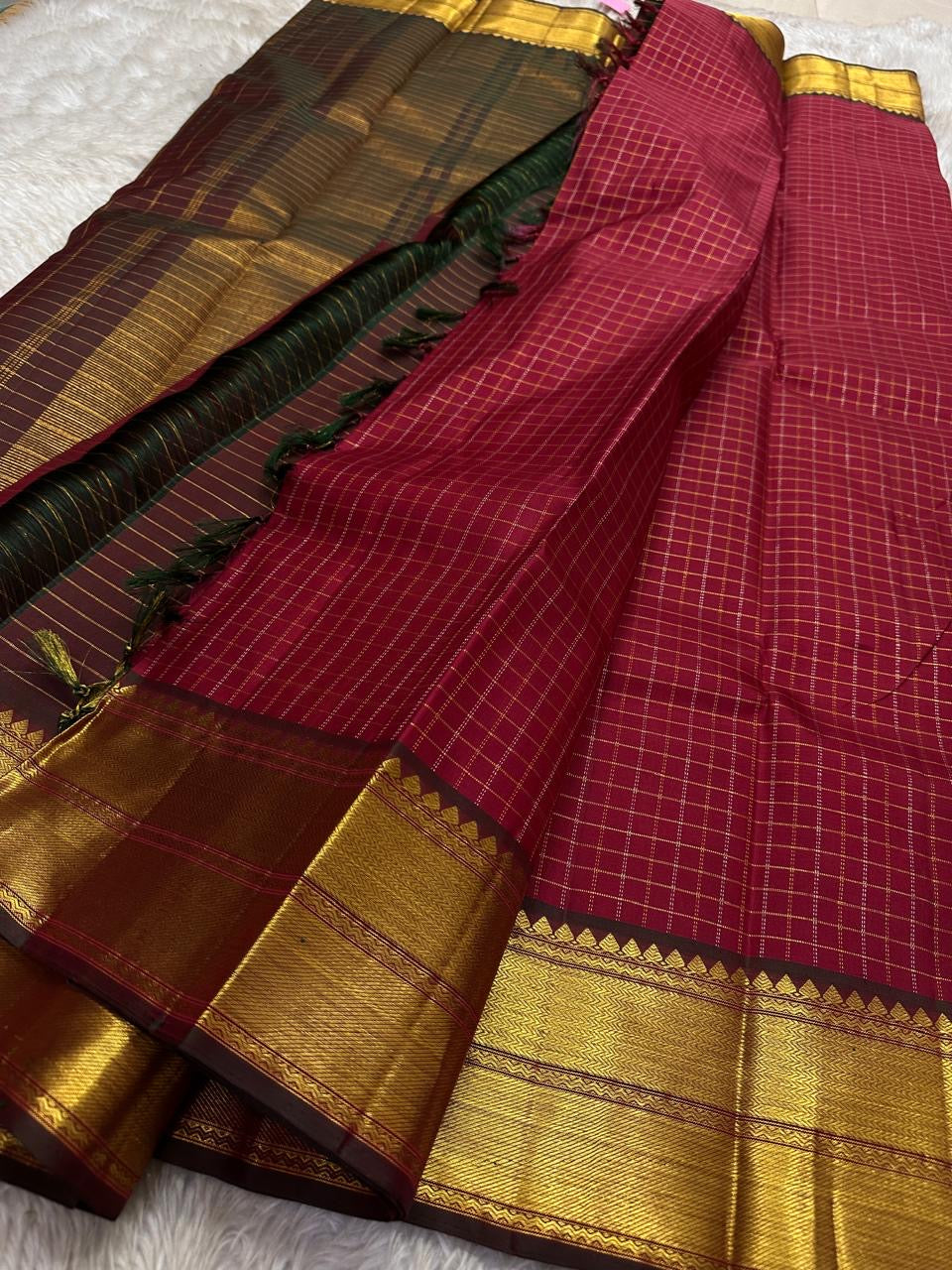 Ruby Zari Kattam – Pure Kanchipuram Silk Saree
Rich Ruby Red Body with Gold Zari Checks
Broad Golden Border with Maroon Highlights & Temple Motifs
Dual-Toned Maroon-Green Pallu with Intricate Zari Weaves
Silk Mark Certified, delivery in 2 weeks