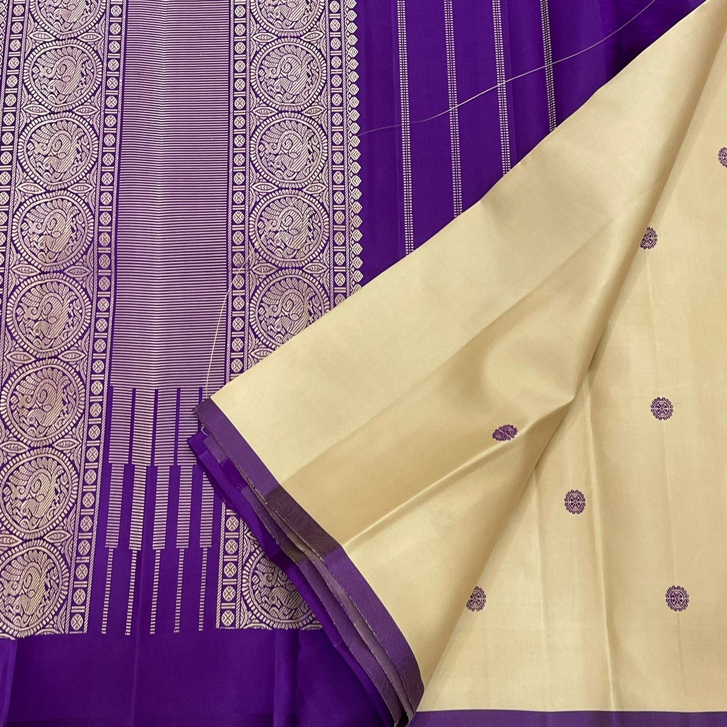 Paal Vadamalli Chakram – Pure Kanchipuram Silk Saree
Ivory body with royal-purple floral coin thread buttas
Grand purple pallu with zari panels & striped center
Handloom Double Warp Weave | Silk Mark Certified | Fall & Pico Done
Free shipping