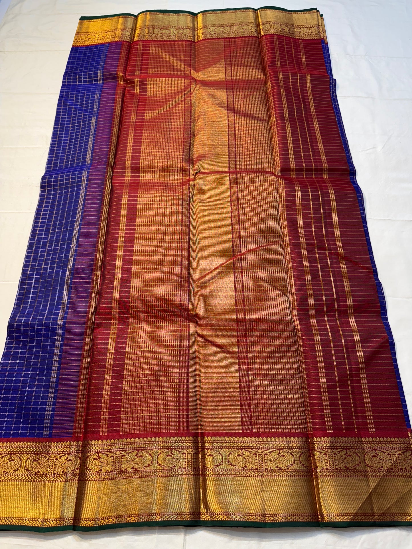 Neela Ratnam — Pure Silk Kanchipuram
• Cobalt-blue kattam checks with antique-gold zari
• Ruby-maroon contrast pallu with grand zari work
• Floral vine borders with bottle-green selvedge
• Silk Mark Certified • Ships in Two Weeks • Free Shipping withi