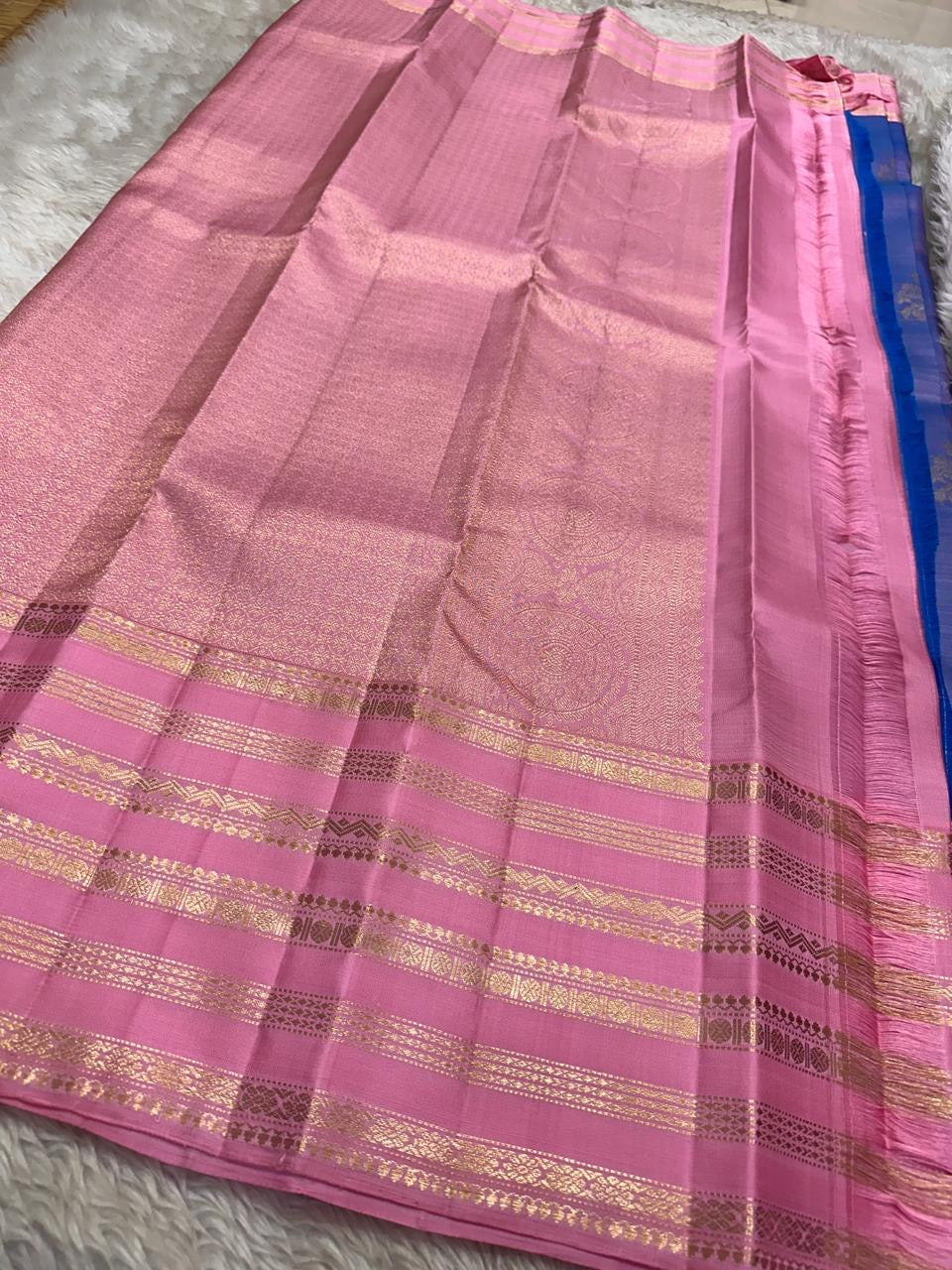 Ramyam, meaning pleasant and delightful, features a mesmerizing blue–purple shot body that shimmers with every movement. Its radiant pink korvai border and pallu, adorned with traditional Varisaipet zari stripes, add festive brilliance.silk mark certified