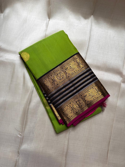 Kili Pachai — Pure Silk Kanchipuram Saree
Parrot-Green Body with Gold Buttas ✨
Black Korvai Borders with Peacock Medallions 🦚
Black Brocade Pallu • Contrast Black Blouse with Zari 🌸
Silk Mark Certified • Free Shipping within USA • Ships in Two Weeks