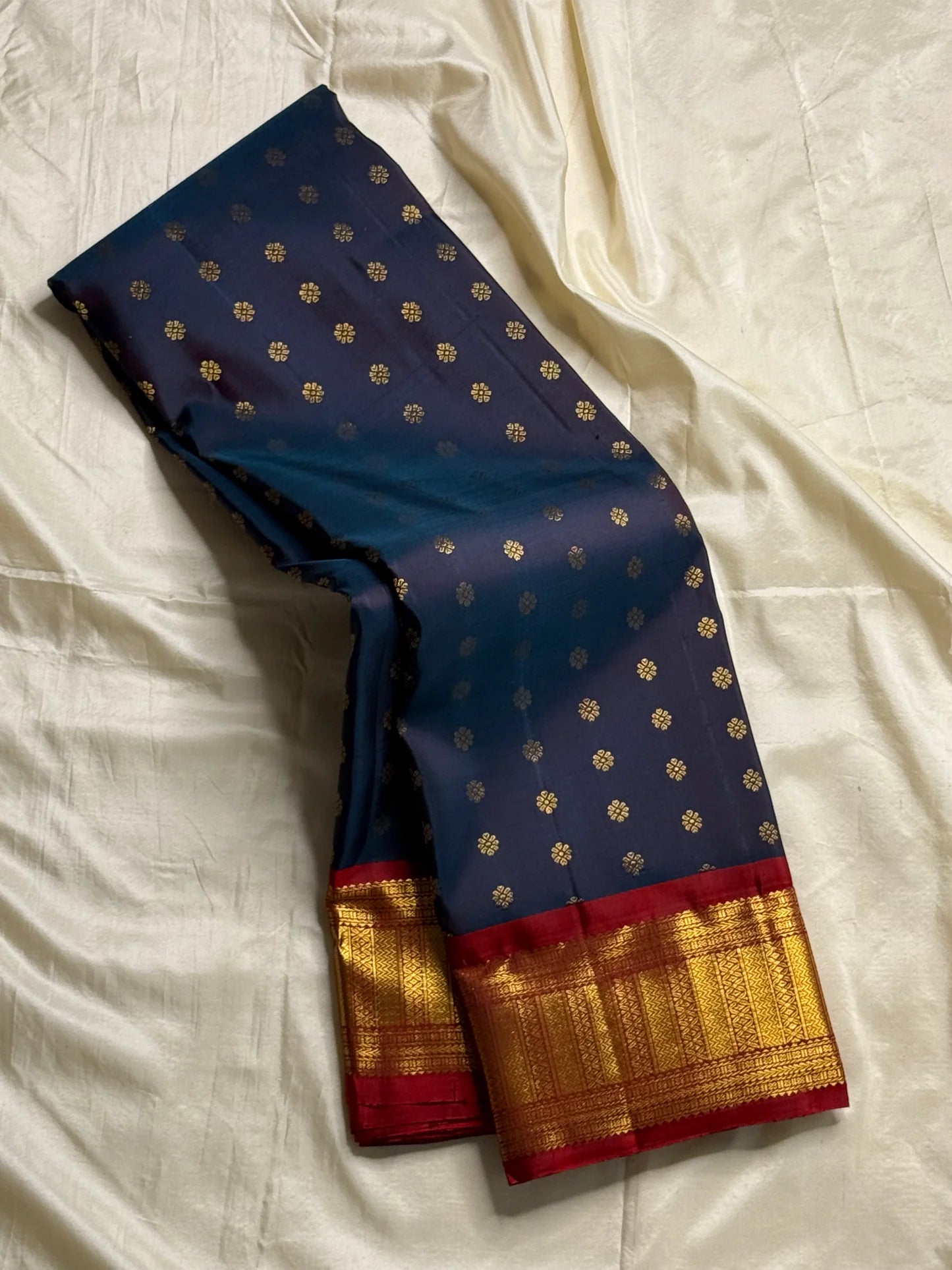 Midnight Neelam Flower Butta — Kanchipuram Pure Silk
Deep midnight neelam (navy) body with scattered gold flower buttas
Korvai contrast maroon borders with grand + geometric zAri motifs 
Rich zari pallū with ornamental motifs; hand-twisted tassels