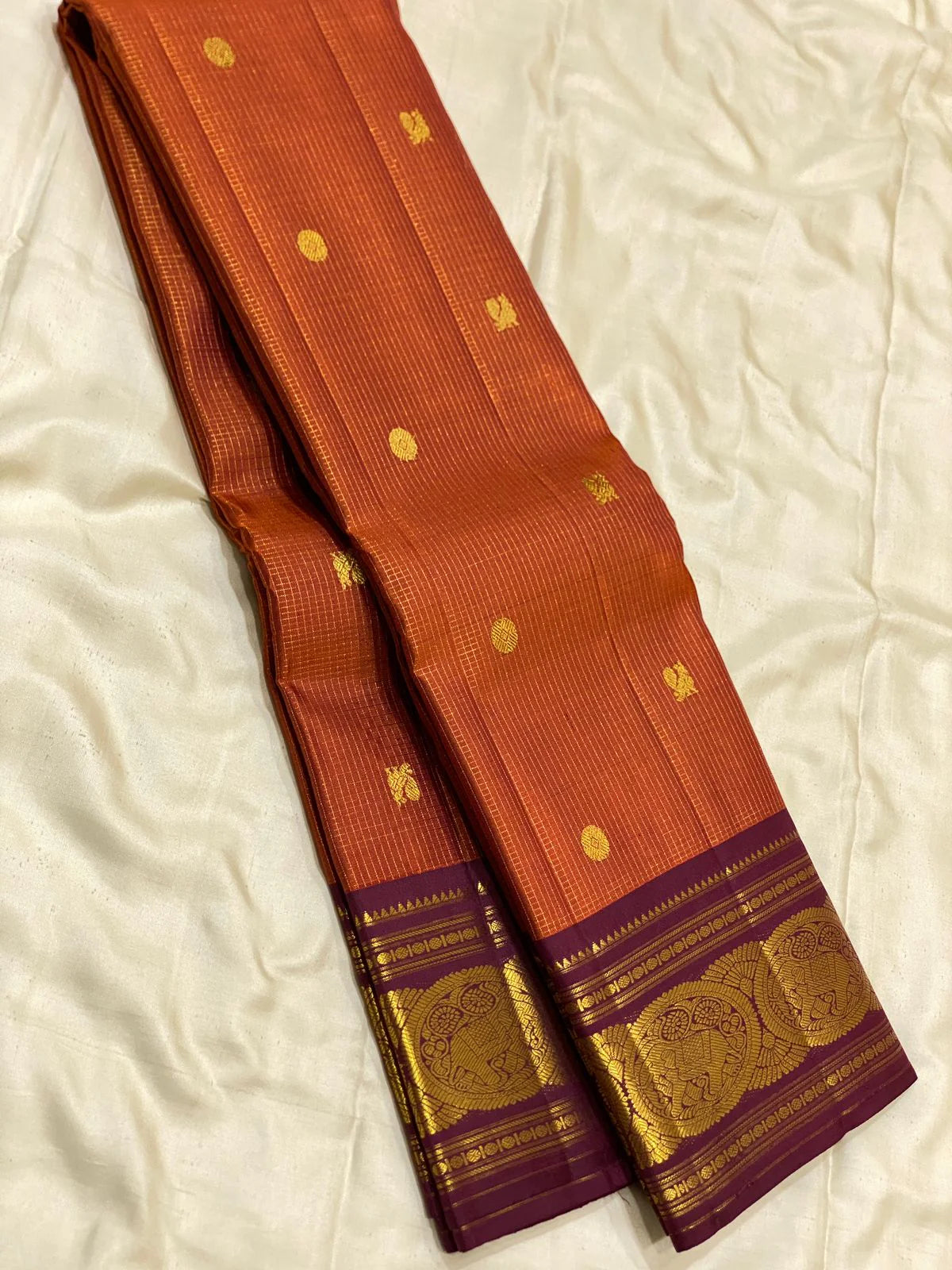 Uma 🌺 – Rust-Orange Kanchipuram Pure Silk Saree
Wide Deep Aubergine-Brown Borders with Sorgavasal Yaanai (Temple Elephant) Motifs
Rich Gold Brocade Pallu with Diamond pettu& Floral Vines