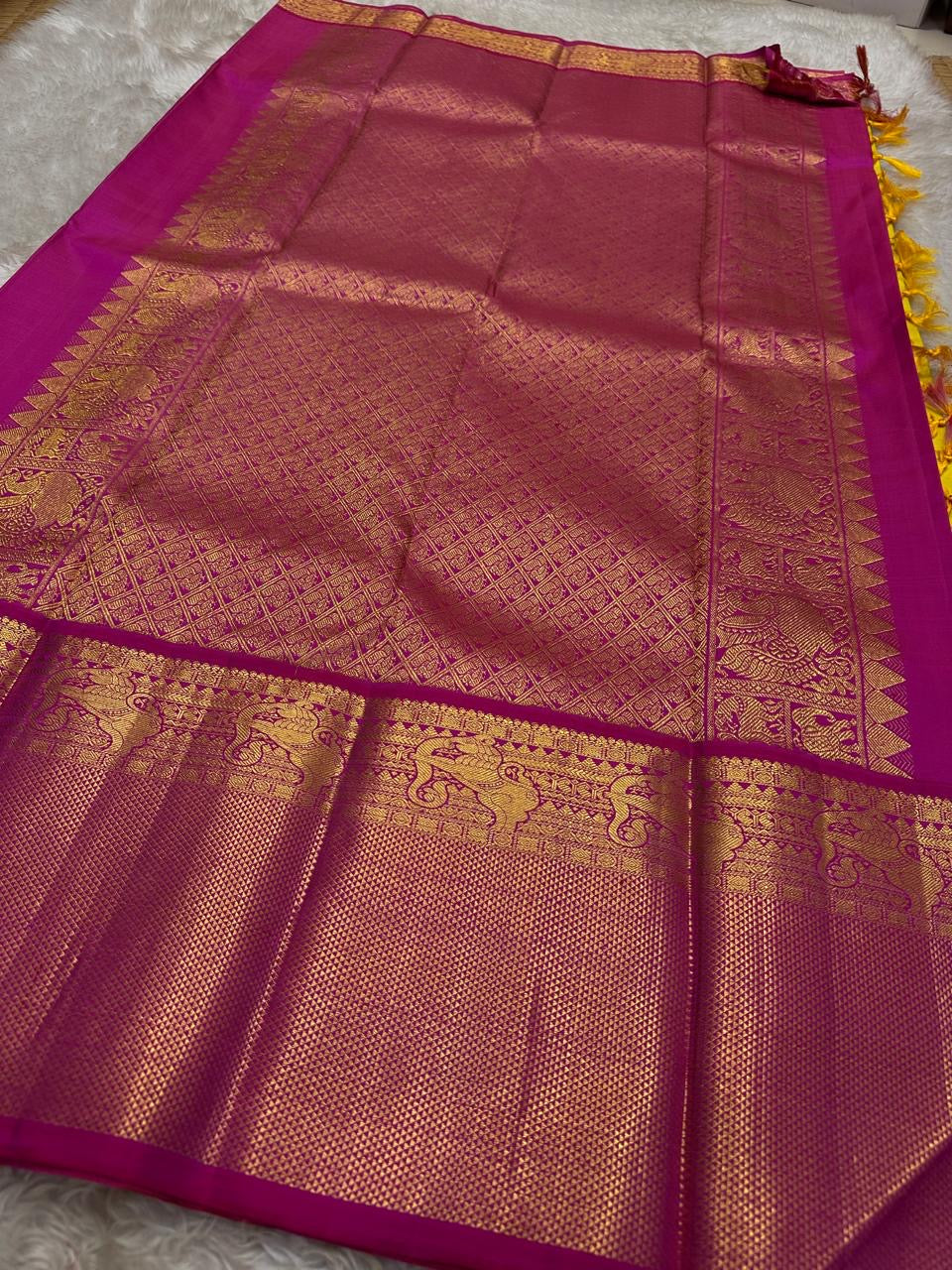Crafted from pure Kanchipuram silk, this golden yellow saree features a broad pink border with traditional Yali motifs. The pallu is richly woven with bold elephant designs in thick zari—an elegant blend of heritage and grandeur.