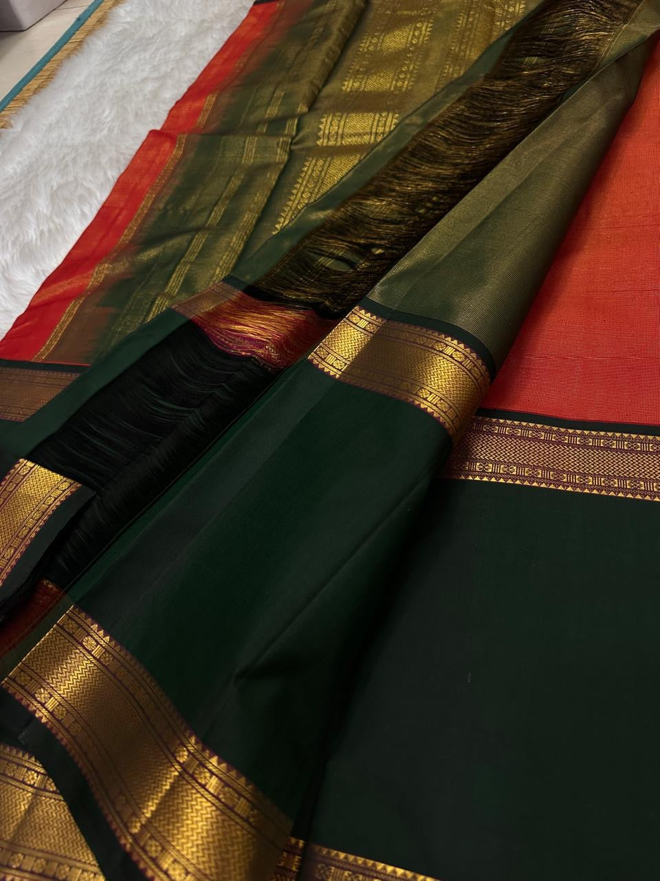 A festive radiant orange silk saree with a rich vairaoosi all over bottle green border, woven to celebrate tradition with a bold flair.