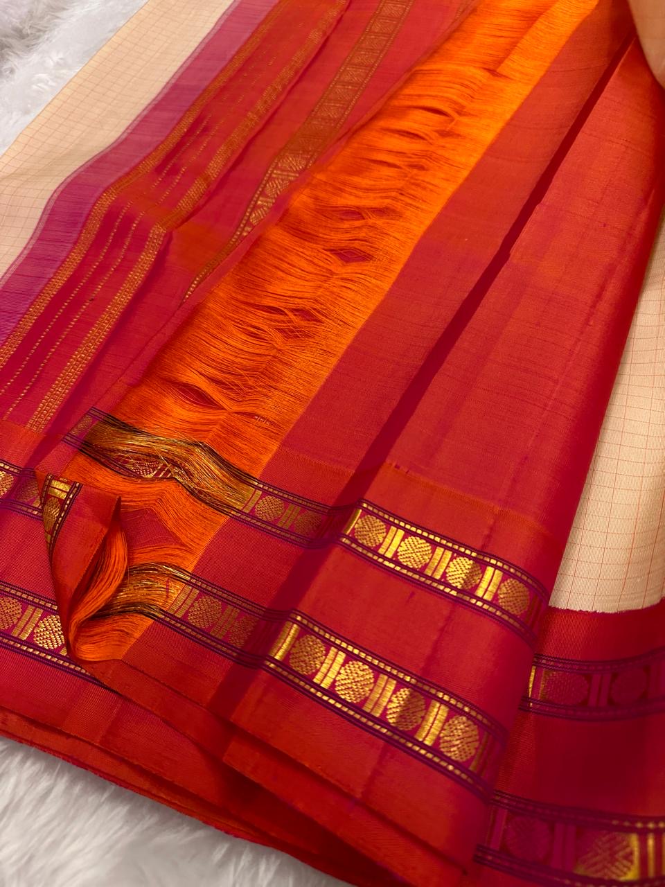 Sharvani Red– Cream Checked Silk Saree with Red Orange shot color Zari Border & Vibrant Pallu
A timeless silk saree featuring a cream body with delicate red checks, complemented by a striking red zari border pallu.