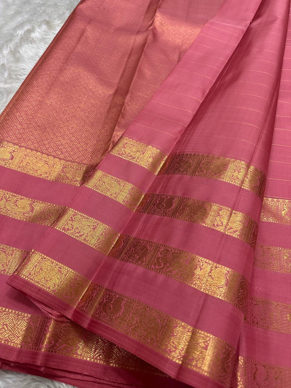 vasantham pink – Handwoven Kanchipuram Silk Saree
A poem in pink silk. The body glows in a serene rose pink, softly accented by delicate gold vertical lines and dainty gold zari buttas that glint like little blessings.