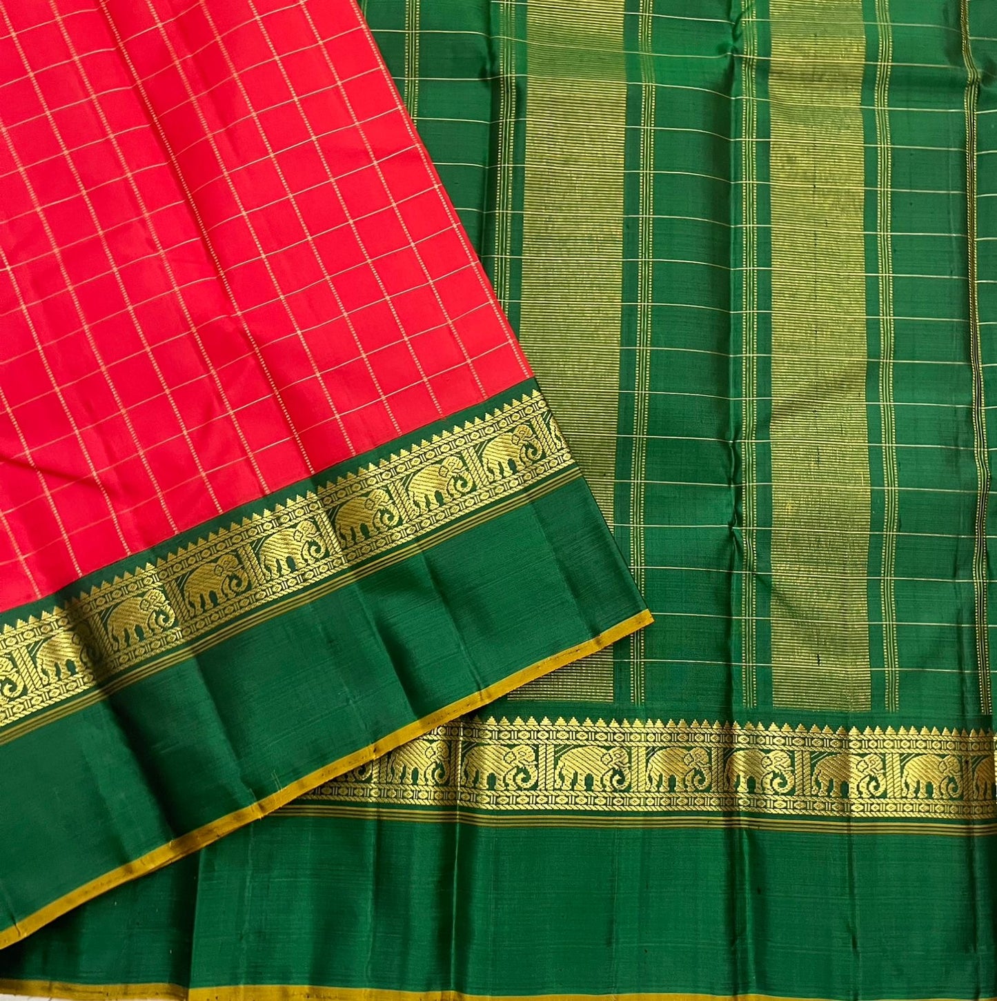 Emerald Ruby Korvai
Pure Kanchipuram Silk Saree – Ruby Red Body with muthu kattam Grid Checks
Emerald Green Korvai Borders Adorned with Zari Elephant Motifs
Grand Green Zari seer Pallu with Traditional motifs
Silk mark certified, ships in 2 weeks