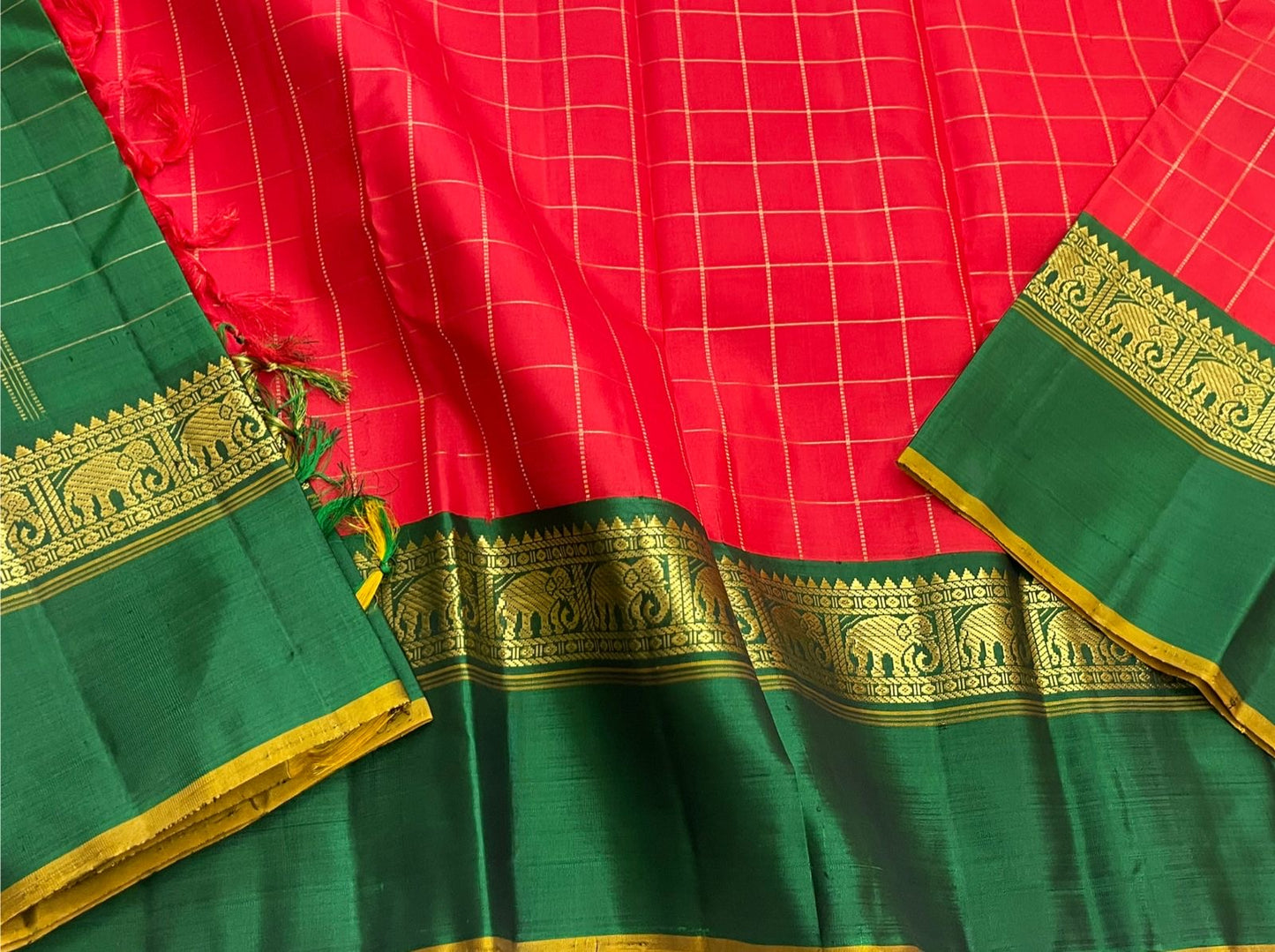 Emerald Ruby Korvai
Pure Kanchipuram Silk Saree – Ruby Red Body with muthu kattam Grid Checks
Emerald Green Korvai Borders Adorned with Zari Elephant Motifs
Grand Green Zari seer Pallu with Traditional motifs
Silk mark certified, ships in 2 weeks