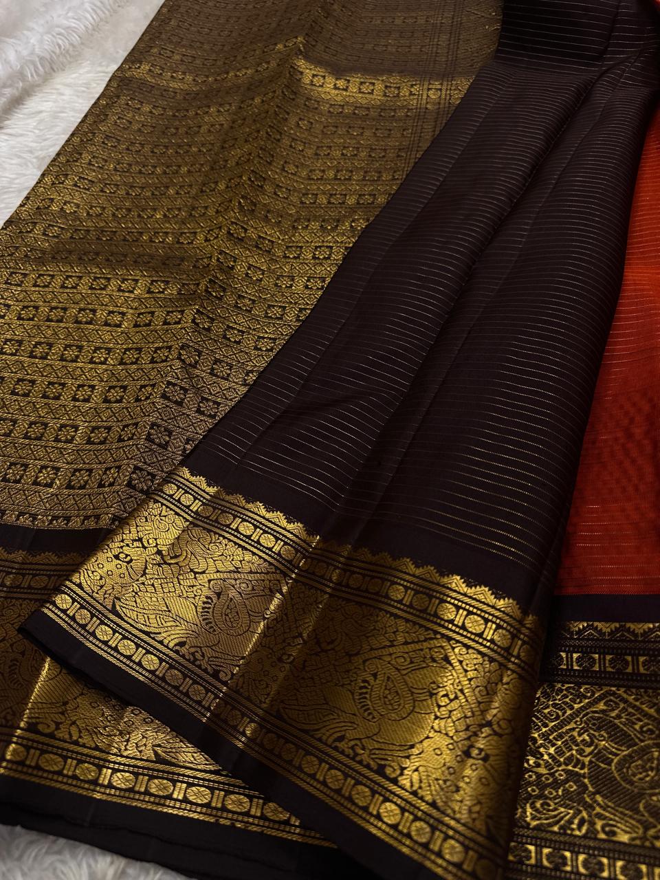 Amber Plume – Pure Kanchipuram Silk Saree
Amber Burnt-Orange Body with Vaira Oosi Stripes
Rudhraksham & Mayil Zari Woven Buttas All Over
Contrast Coffee-Brown Border with Peacock Motif Panel
Silk Mark Certified, delivery in 2 weeks
