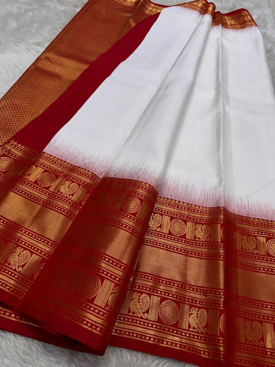 A true festival essential white with dashing red pure silk Kanchipuram saree with a kamalam and mayil detailed border zari work , red reku and Pallu