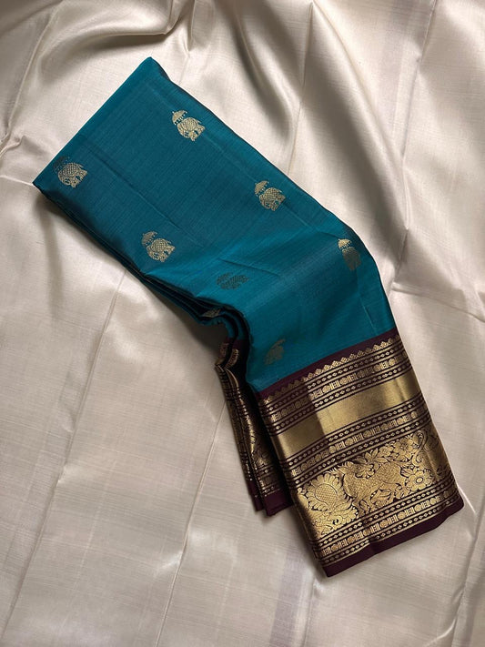 Neeli Megham – Pure Silk Kanchipuram
Teal-blue body with gold annapakshi buttas & aubergine korvai border in antique zari brocade
Silk Mark Certified • Fall & Pico Done • Blouse Stitching Available ($30) • Free Shipping within USA • Ships in Two Weeks