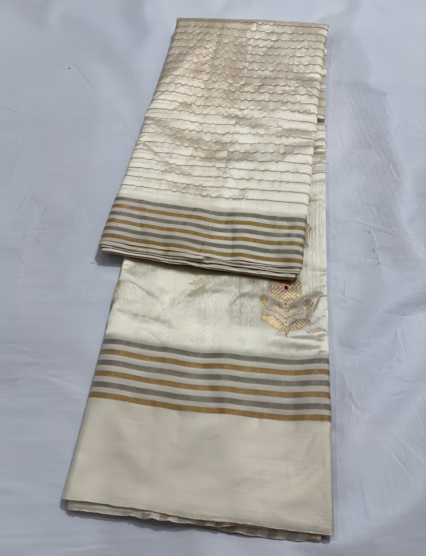 Ivory Cream Chanderi Saree with Gold Zari and Handwoven Sunflower Motifs.
A serene blend of tradition and elegance, with intricate red mina accents. Finished with alternating sona roopa stripes and a richly woven pallu for timeless festive charm