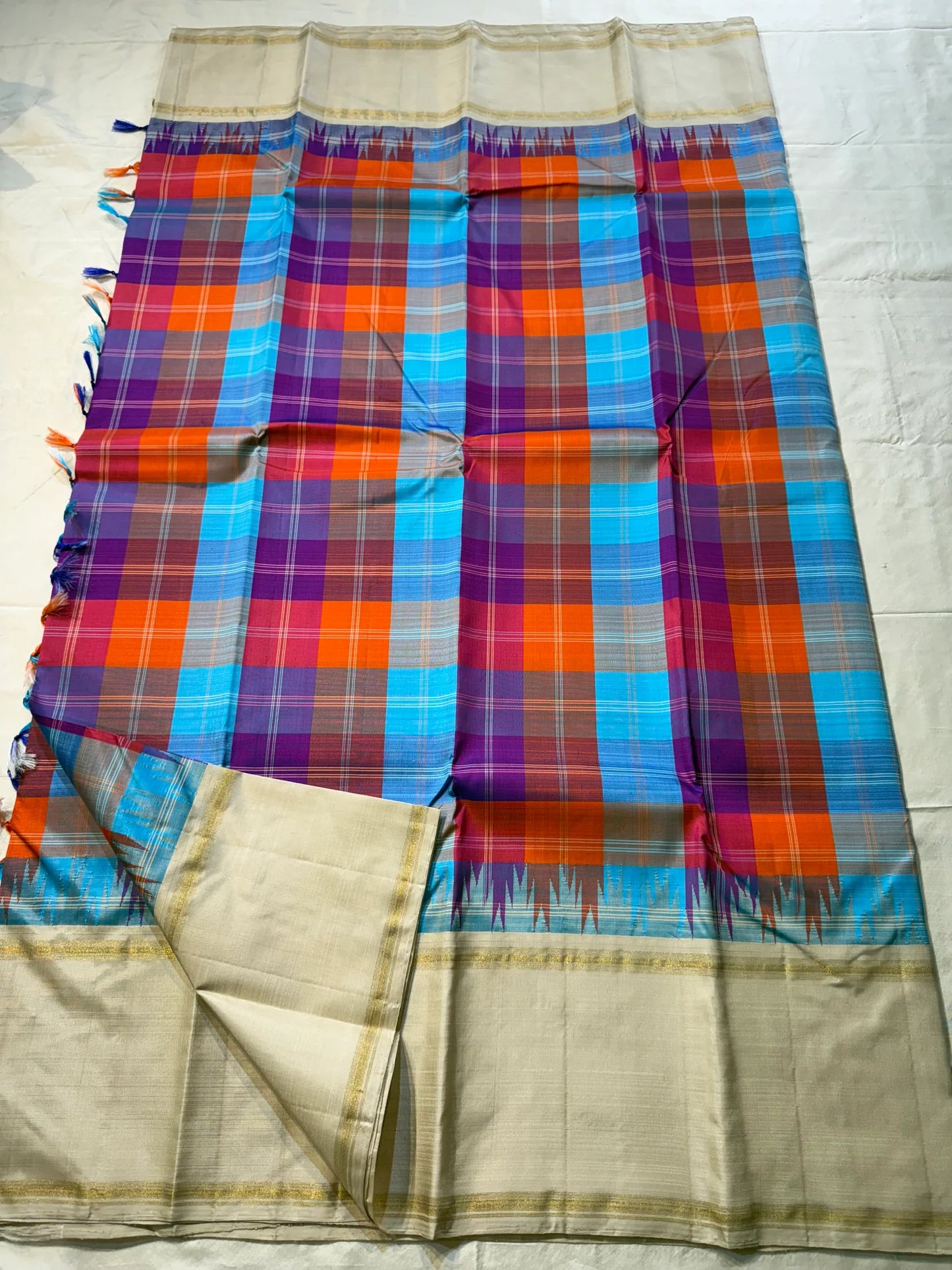 Venpattu Kattam Thazampoo Reku – ivory/venpattu borders with multicolor kattam (checks) body
Pure Kanchipuram silk • rani pink, tangerine, purple, sky blue & steel grey checks with thazampoo reku edging
Ivory pallu with gold tissue stripes & multicolor