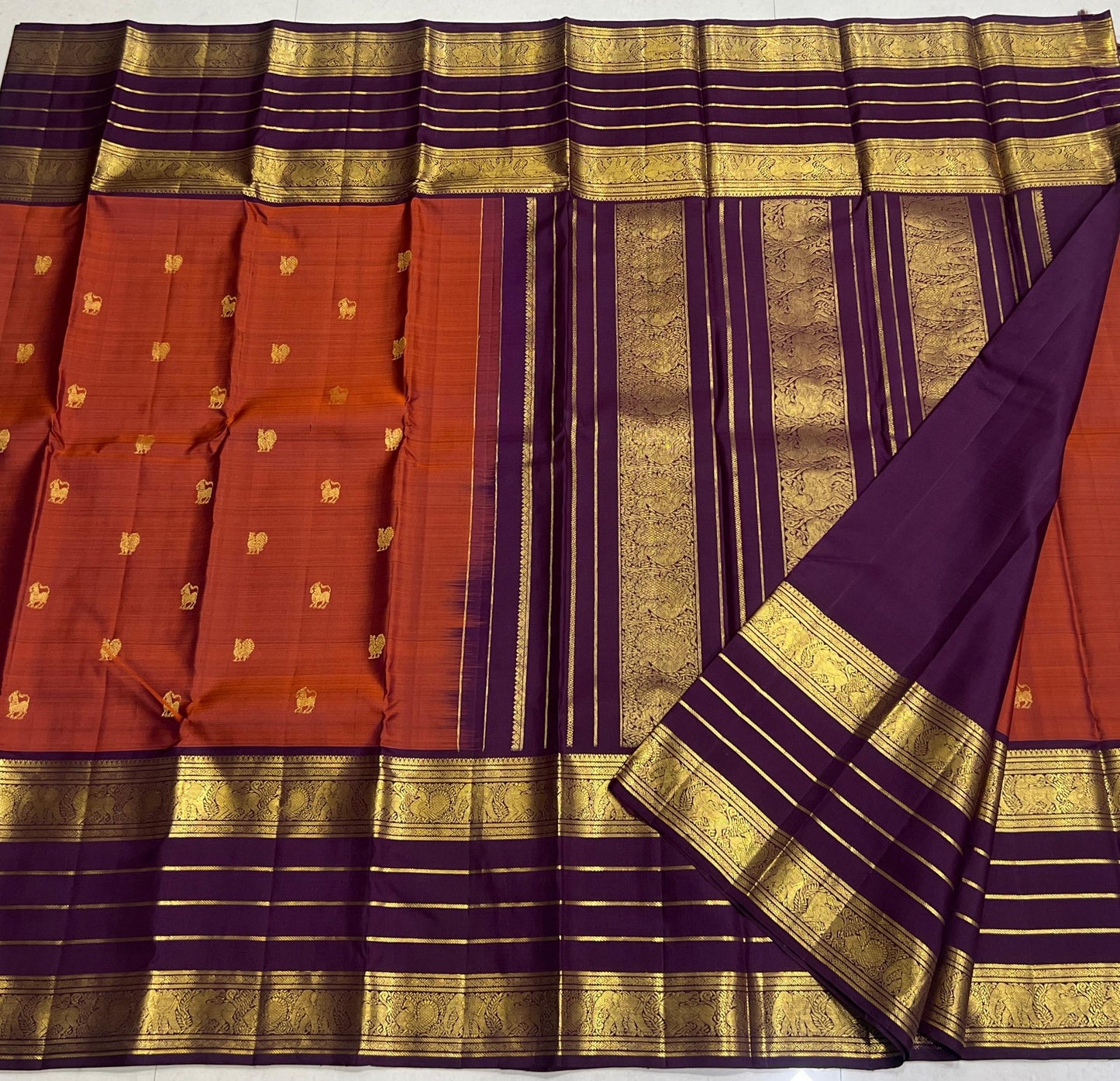 Karpagam – Burnt Orange & Coffee Elegance ✨🪔
A glowing burnt orange body adorned with gold zari peacocks 🦚 and mythical Yazhi 🐉 motifs. The deep coffee border shimmers with Varisaipet geometric zari, while the grand pallu unfolds in panels of Vanasring