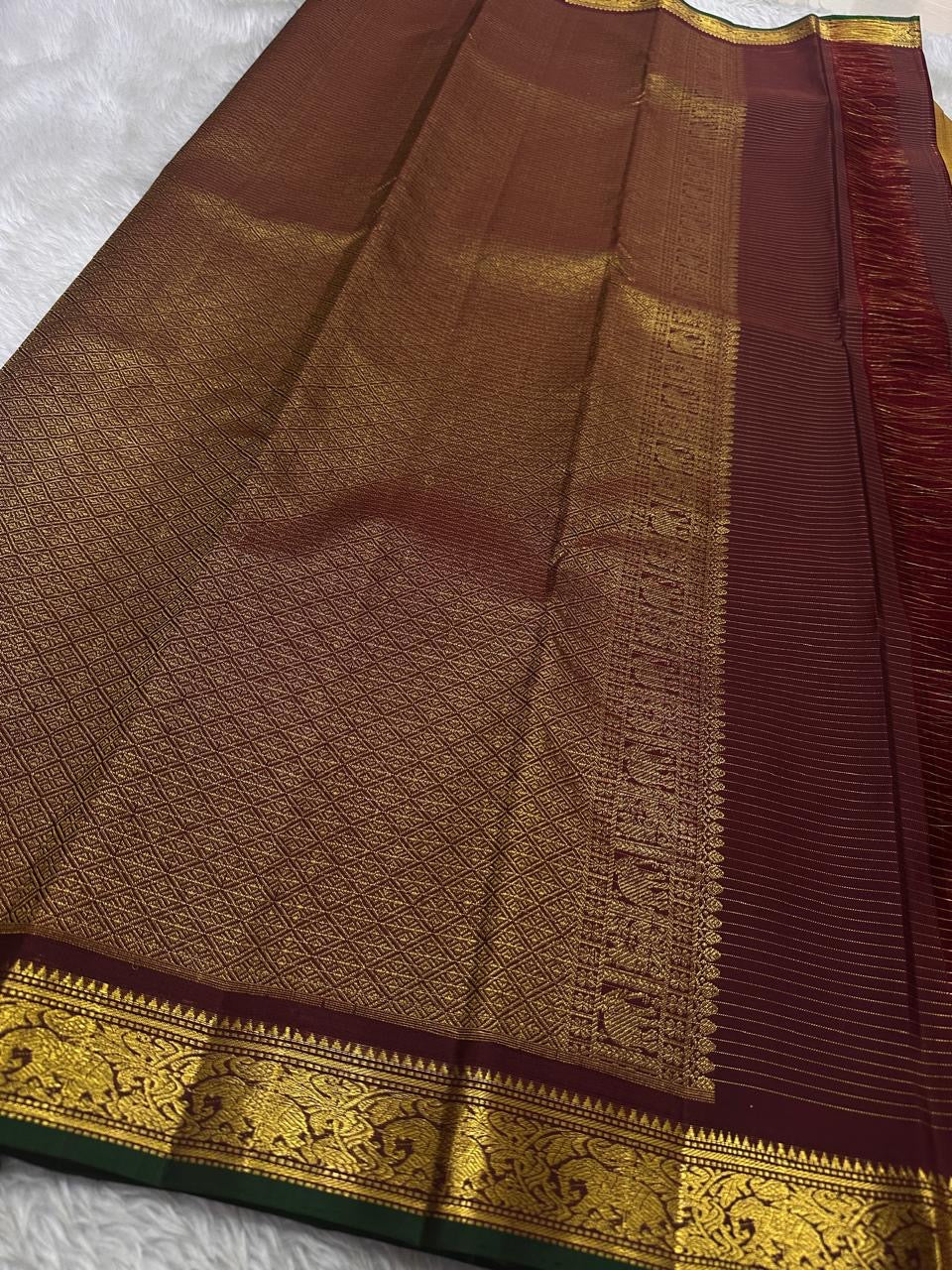 Amber Oosikattam ✨ – Pure Kanchipuram Silk Saree
Burnished Amber-Gold Body in Oosi Zari Kattam with Leaf Buttas
Deep Maroon Korvai Border with Green Selvedge & Elephant Motifs
Regal Maroon Pallu with Intricate Gold Zari Brocade
Silk Mark Certified |