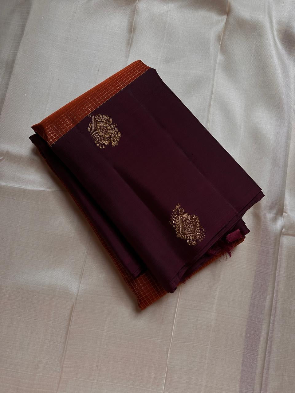 Rust Orange & Wide Broad Silk Korvai – Pure Kanchipuram Silk Saree
Deep wine body adorned with gold ambi buttas for subtle elegance
Contrast rust-orange wide korvai border with podi-kattam micro checks
Grand wine pallu with full-zari diamond jaal