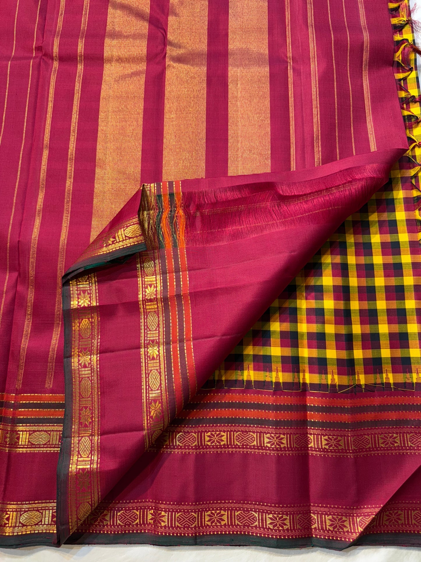 Manjal Maroon Kattam – Pure Kanchipuram Silk Saree
Mustard & Maroon Body with Traditional Multi-Color Checks
Korvai Borders with Floral-Star Zari & Temple Tips
Grand Maroon Pallu with Gold Zari Stripes & Tassels
Silk Mark Certified | ships in 2 weeks
