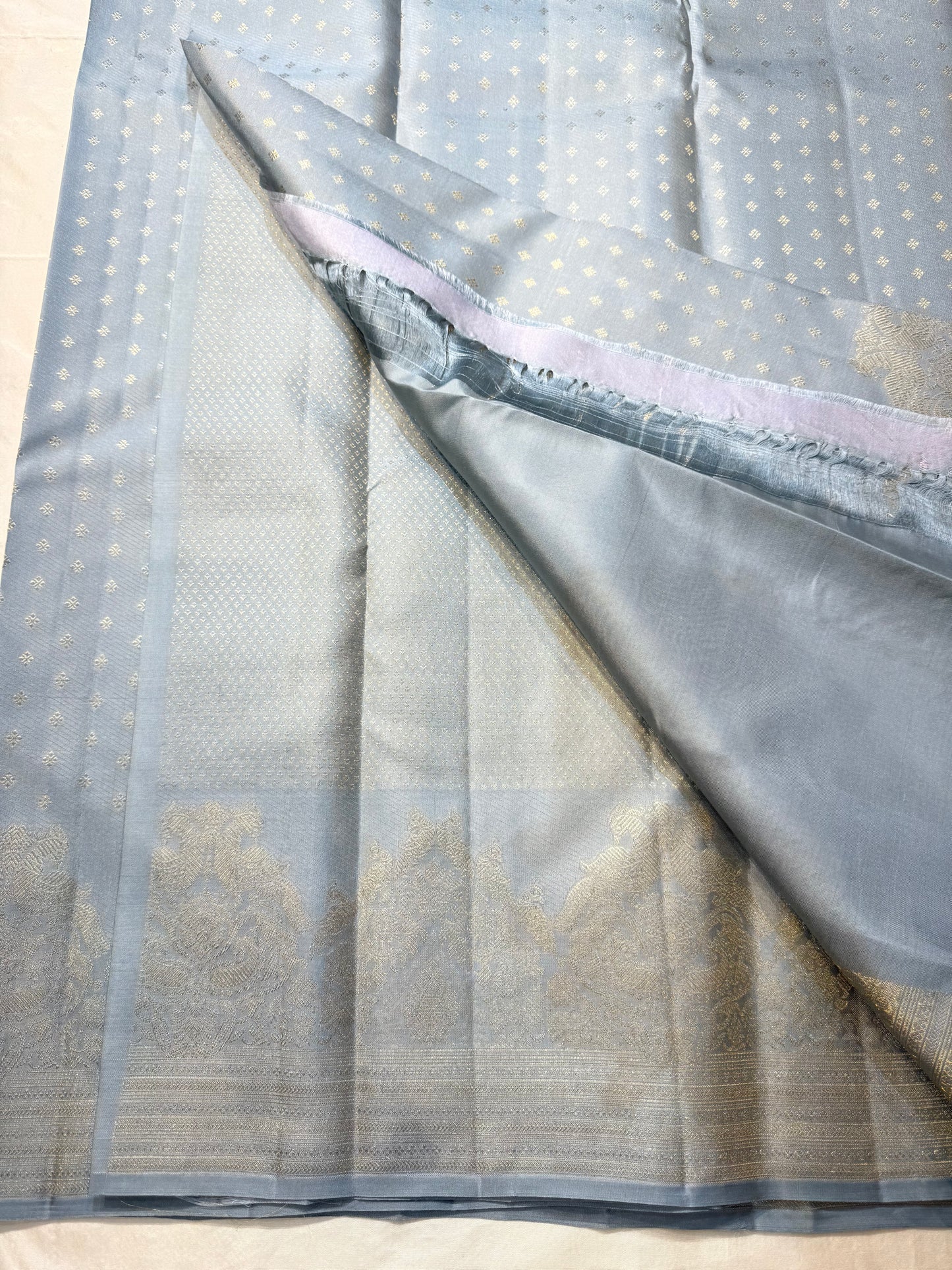 Chamomile — Kanchipuram Pure Silk
Pale gray-blue body with silver roopa buttas all over
Temple gopuram-inspired zari borders in luminous silver
Rich silver brocade pallu with intricate detailing
Silk Mark Certified • Free Shipping within USA