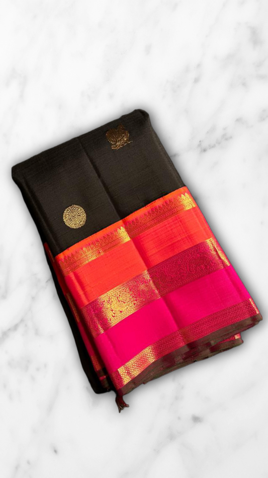 Kanmani — Black & Rani Pure Silk Kanchipuram Saree
Inky black body with gold medallion & peacock buttas
Striking rani-pink and kavi-orange korvai borders with temple-edge zari
Rich rani-pink brocade pallu with grid jaal & heritage vines
Silk Mark Cert