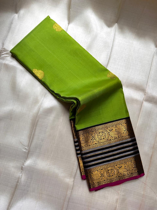 Kili Pachai — Pure Silk Kanchipuram Saree
Parrot-Green Body with Gold Buttas ✨
Black Korvai Borders with Peacock Medallions 🦚
Black Brocade Pallu • Contrast Black Blouse with Zari 🌸
Silk Mark Certified • Free Shipping within USA • Ships in Two Weeks