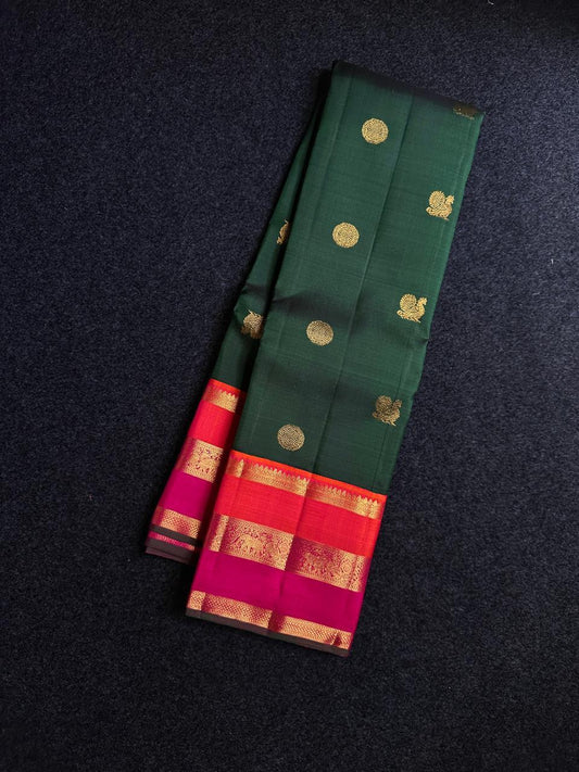 Varna Jaalam Green — Pure Silk Kanchipuram
Bottle-green body with gold chakram & mayil buttas, korvai pink-orange border
Silk Mark Certified • Free USA Shipping • Ships in Two Weeks ✅