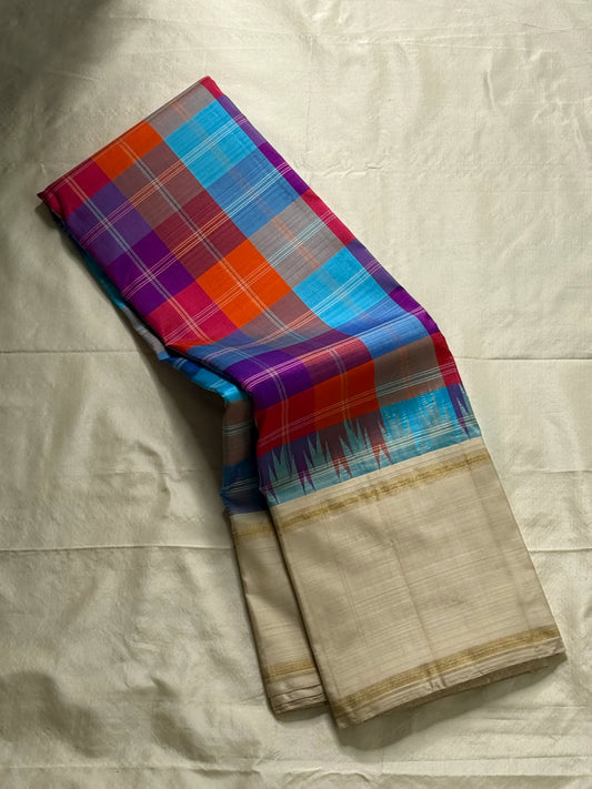 Venpattu Kattam Thazampoo Reku – ivory/venpattu borders with multicolor kattam (checks) body
Pure Kanchipuram silk • rani pink, tangerine, purple, sky blue & steel grey checks with thazampoo reku edging
Ivory pallu with gold tissue stripes & multicolor