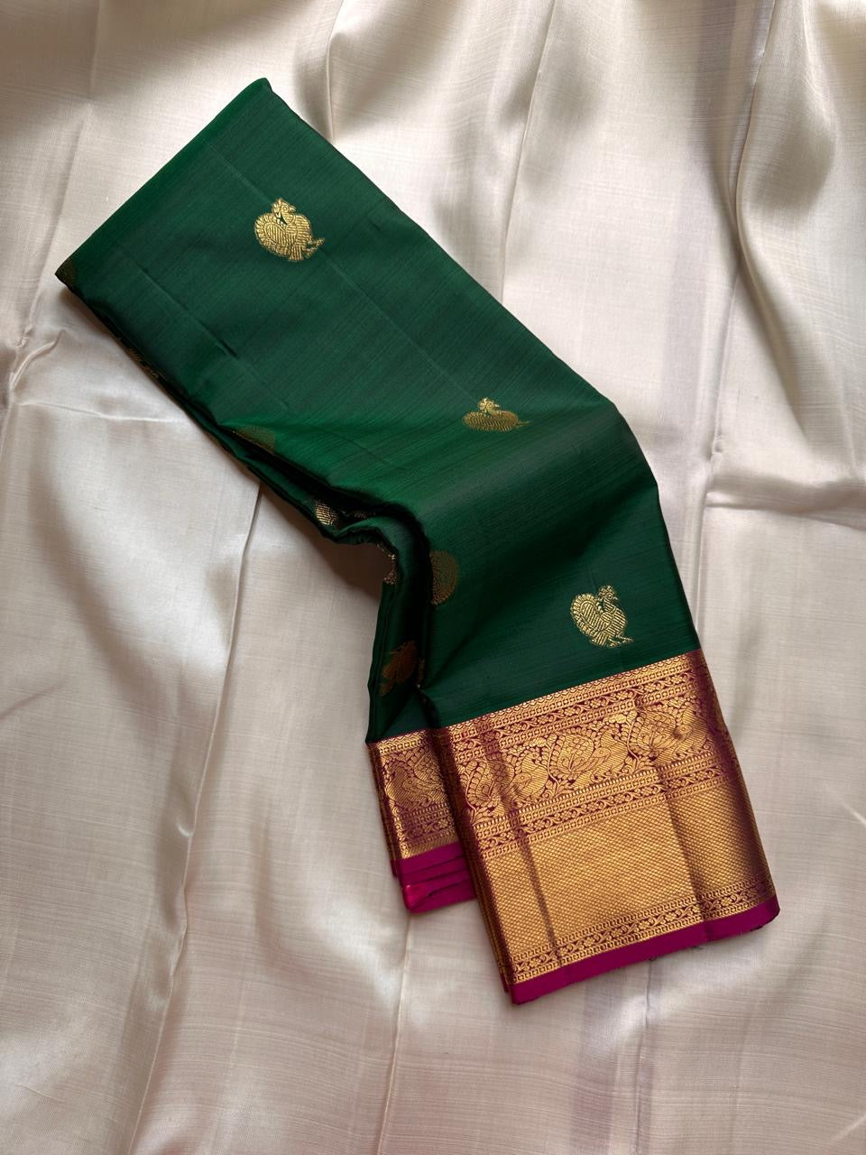 Maragatha Mayil Butta — Kanchipuram Pure Silk
Emerald green (maragatham) body with gold mayil/peacock buttas
Contrast rani-magenta korvai borders & zari-rich pallu
Silk Mark Certified | Free Shipping within USA
