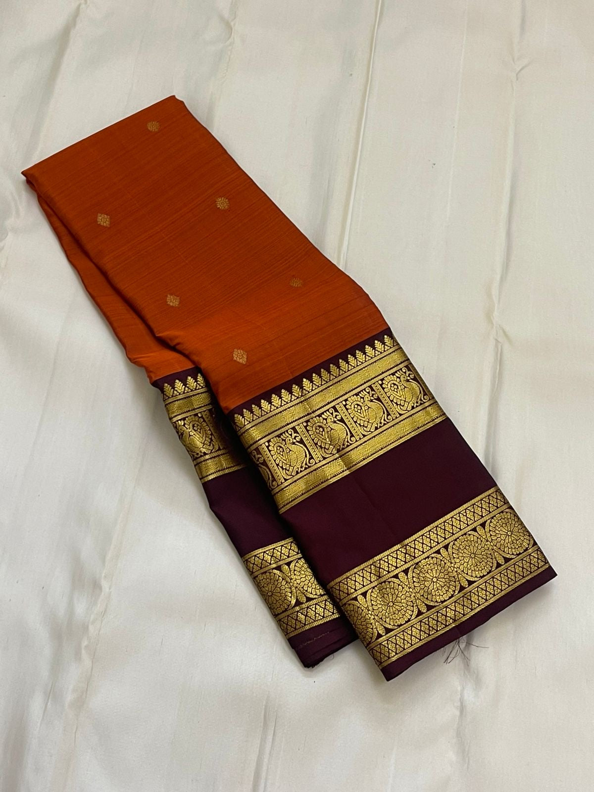 Rust Orange Ramyam – Pure Kanchipuram Silk Saree
Rust-orange body with pavin coin  buttas
Deep brown border with peacock panel & chakra medallions; grand zari pallu
Silk Mark Certified | Blouse Piece Included | Fall & Pico Done
Free Shipping in 1 week