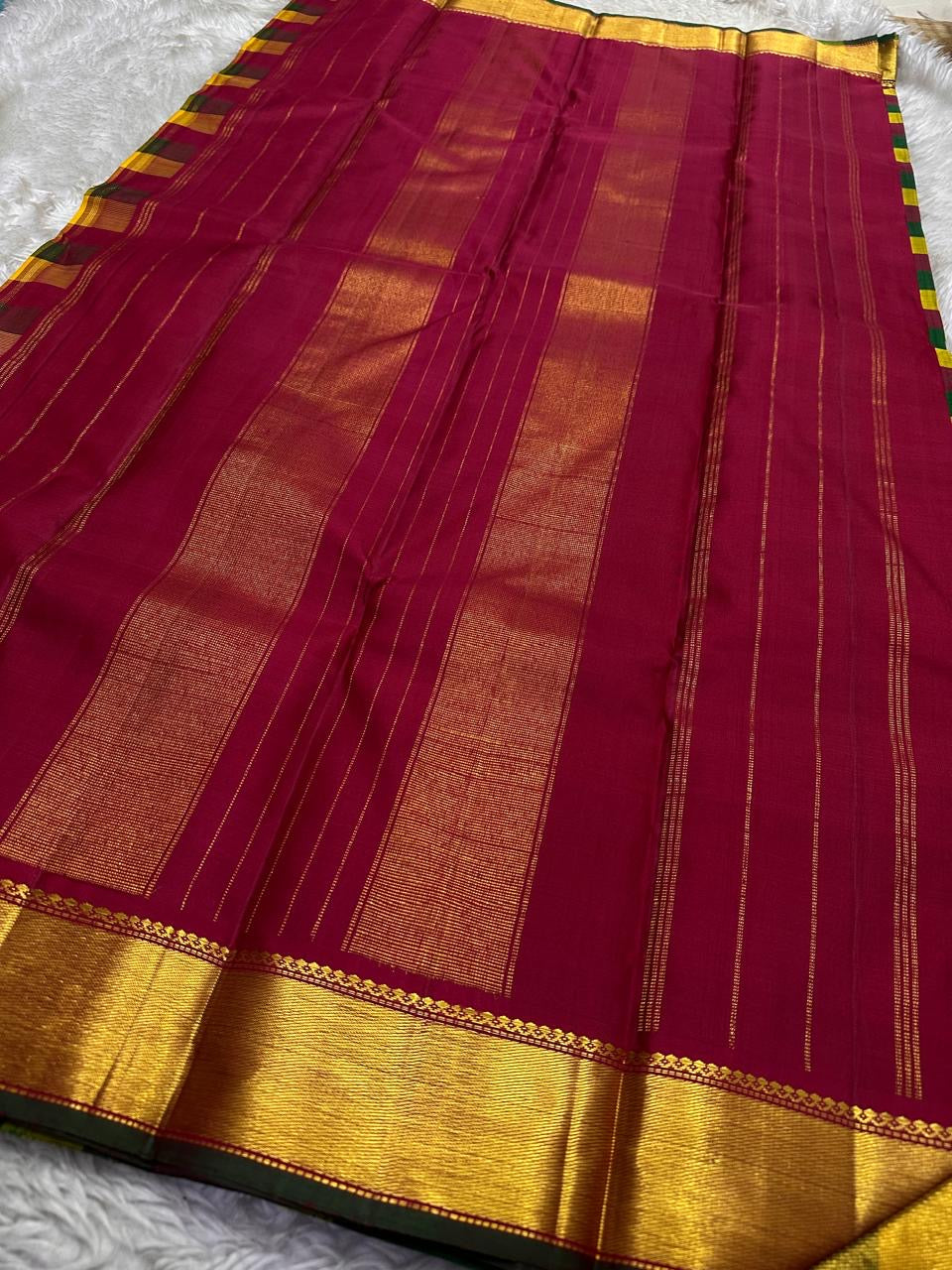 Full wine pallu spread with zari woven vertical lines and broad gold zari border finish