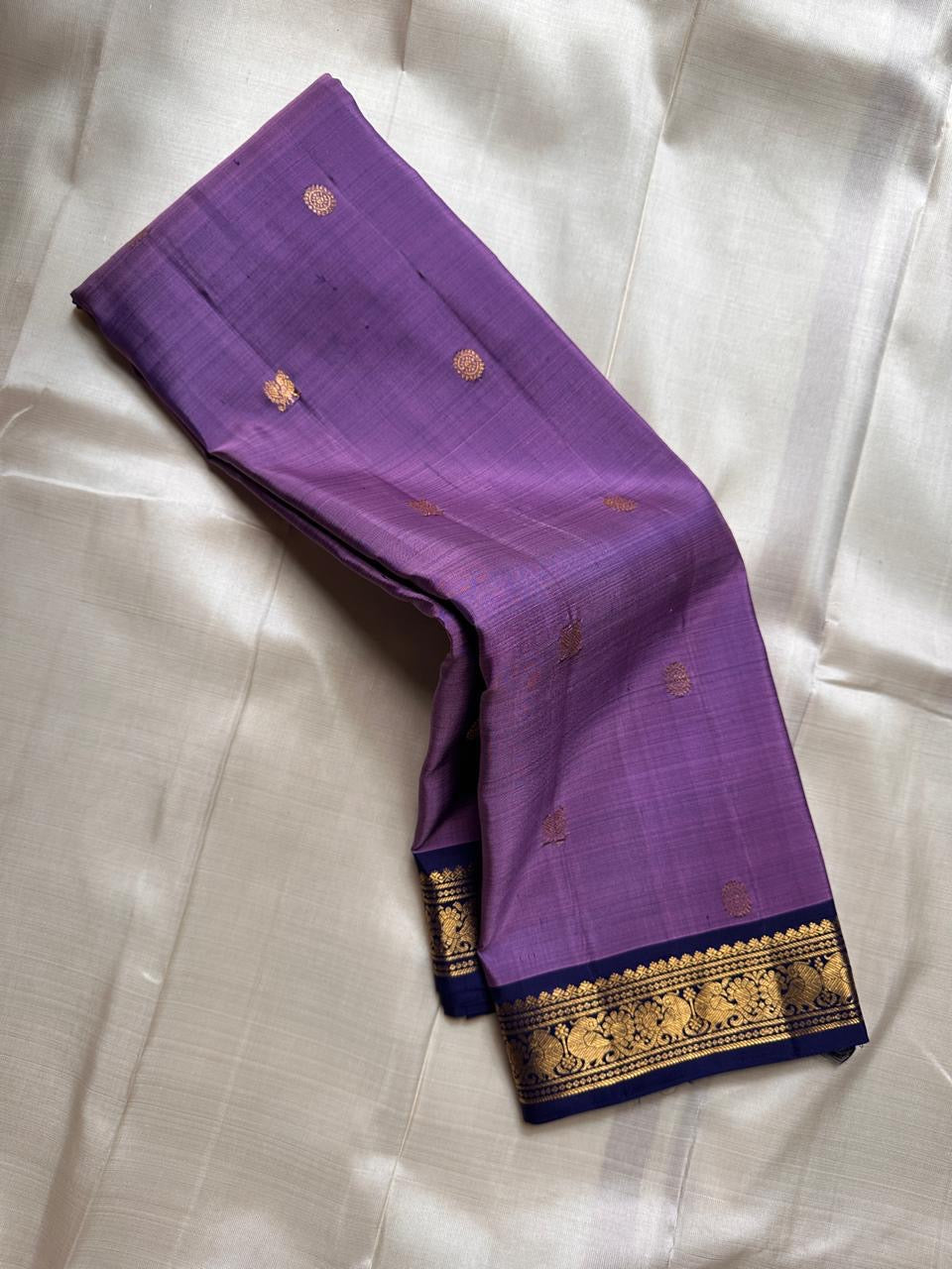 Lilac Mayil Pushpam – lilac-purple body with navy korvai borders
Pure Kanchipuram silk • gold zari pushpam (flower) buttas all over
Grand navy brocade pallu with diamond jaal • contrast blouse with border
Silk Mark Certified | Fall & Pico Done |
