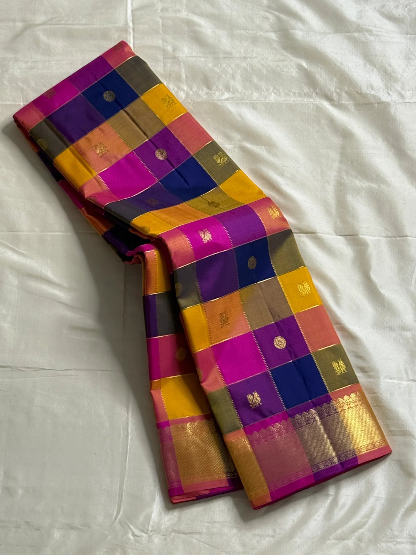Navaranga Kattam — Multi-Color Paalum pazhamum checks  Kanchipuram Pure Silk
Rani-magenta contrast border & rich zari pallū 
Gold coin & peacock buttas over jewel-tone squares
Handloom Kanchipuram • Matching magenta blouse with borders