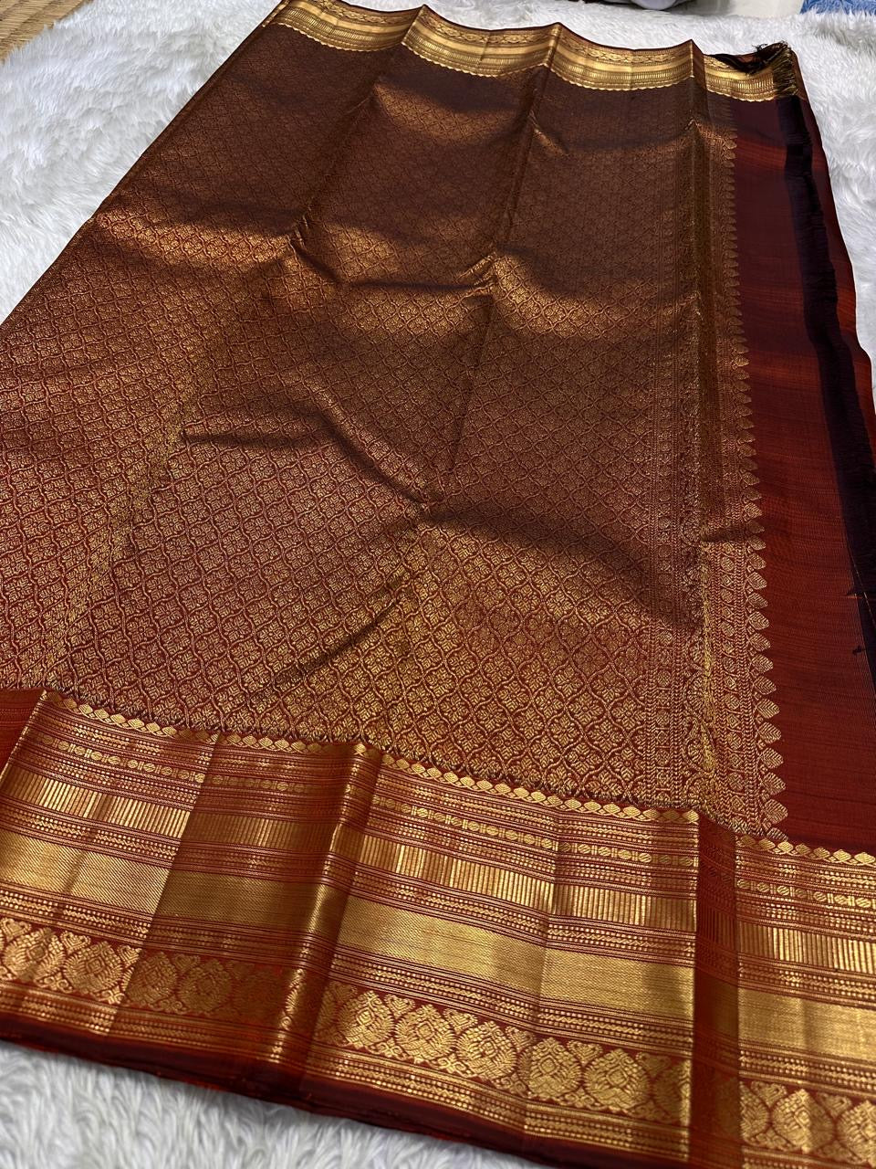 Gilded Rust – Pure Kanchipuram Silk Saree
Deep rust body with delicate paisley zari buttas 🌿
Antique-gold border featuring kaddi stripes & floral motifs ✨
Grand brocade pallu with lattice jaal & floral vines 🕊️
Silk Mark Certified, delivery in 2 weeks