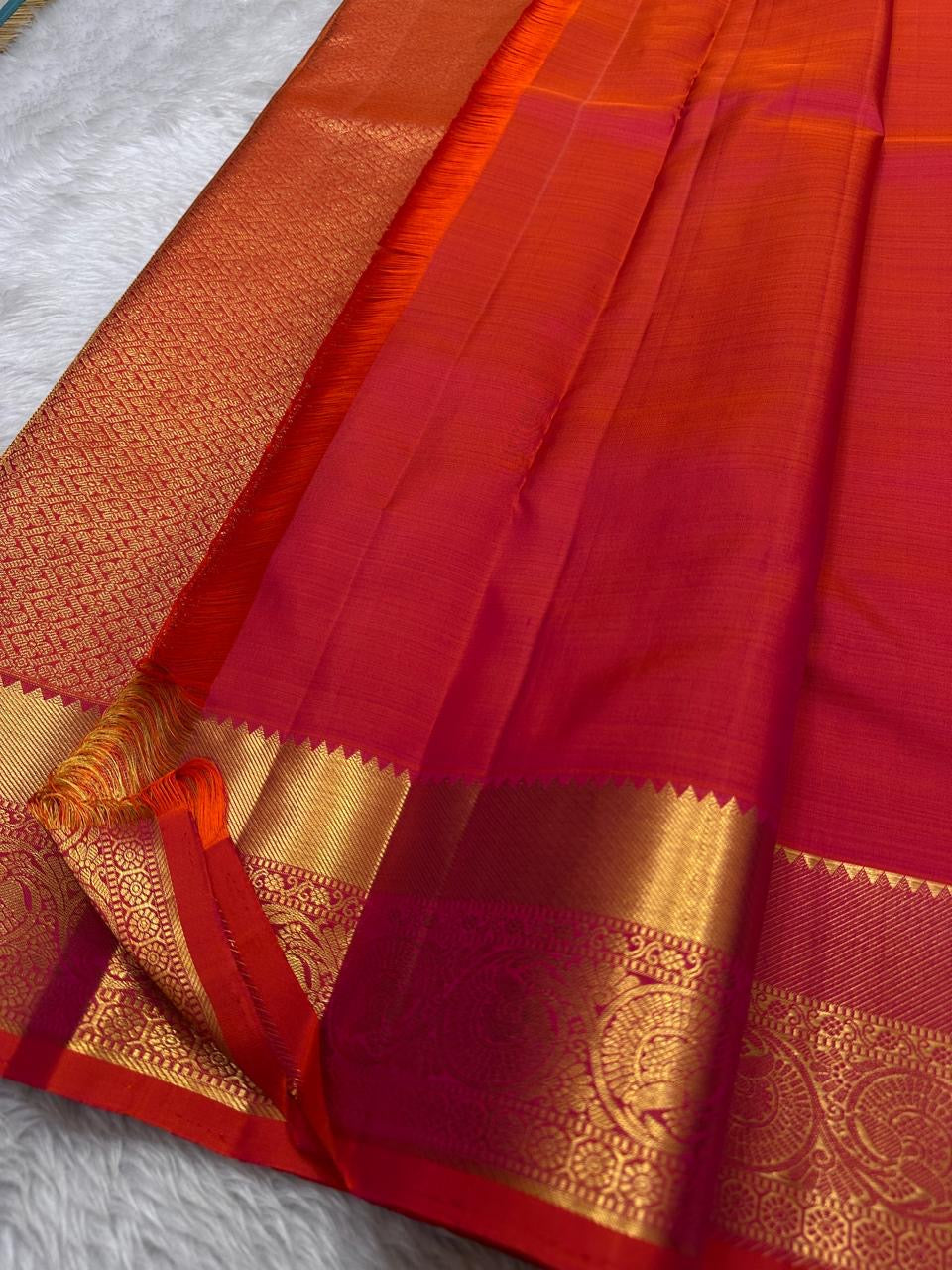 Agnika – Tomato orange shot Red Kanchipuram Silk Saree with Mayil Chakram Butta & Orange Border
Fiery and regal, Agnika is a pure Kanchipuram silk saree featuring a rich red body adorned with intricate Mayil Chakram buttas.