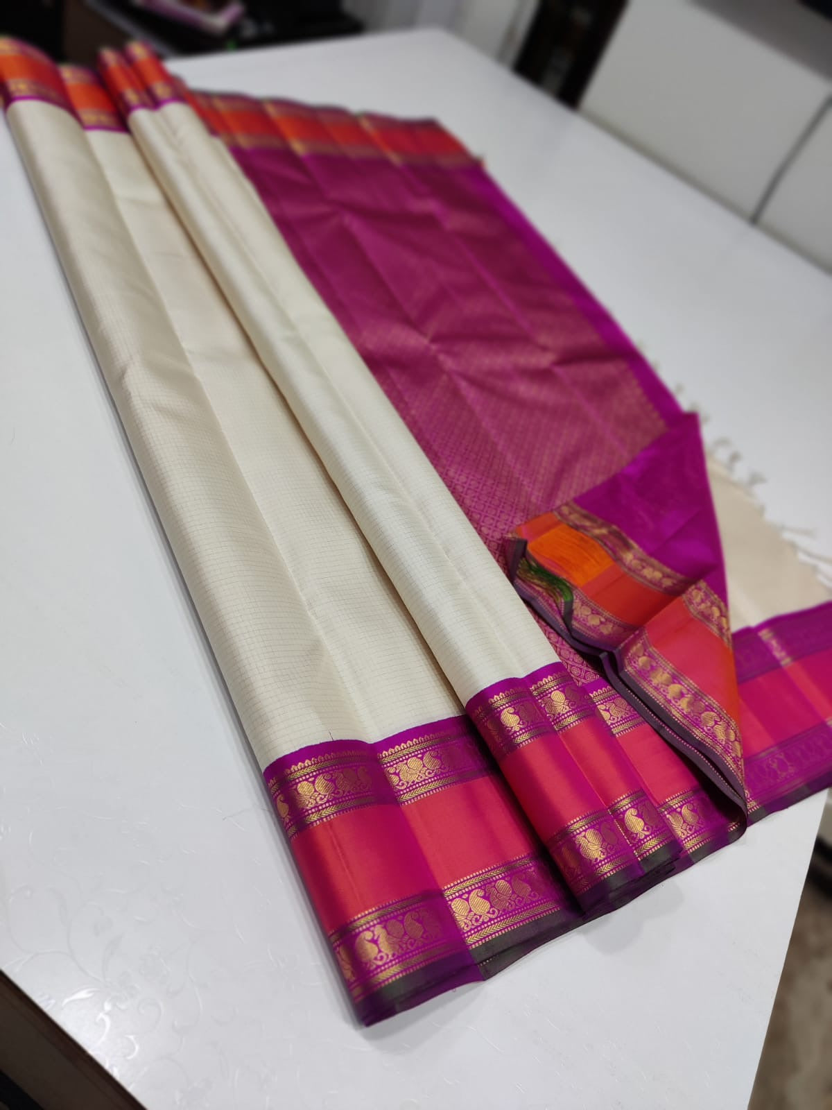 Pearl Lattice – Pure Kanchipuram Silk Saree
Ivory Cream Body with Micro-Checks ✨
Rani-Pink Rettapet Border with Gold Zari
Grand Rani-Pink Brocade Pallu with Traditional Motifs
Silk Mark Certified, delivery in 2 weeks