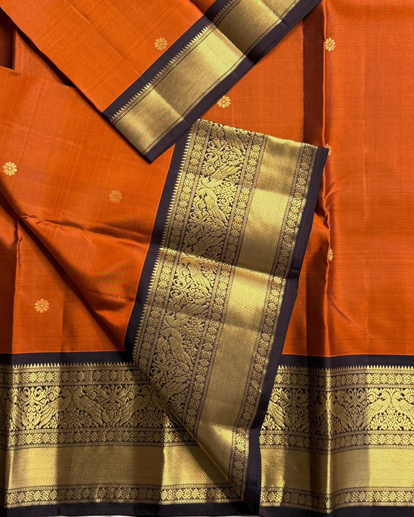 Rust Orange Annam Bloom – Pure Silk Kanchipuram
Rust-orange body with delicate zari buttas 🌸
Aubergine korvai borders with majestic Annam motifs 🪔
Grand aubergine pallu with kasu stripes & tissue weave ✨
Silk Mark Cert • Ships in Two Weeks- chk desc