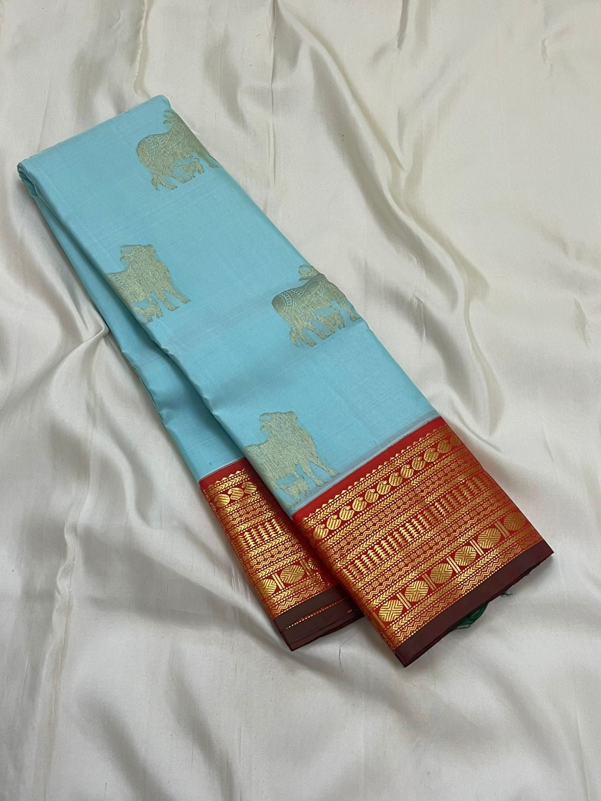 Kamadhenu — Pure Silk Kanchipuram
Sky-blue body with gold Kamadhenu motifs, fiery-orange pallu & ruby-red korvai borders ✨
Silk Mark Certified • Antique Zari Weave • Ships in Two Weeks • Free Shipping within USA