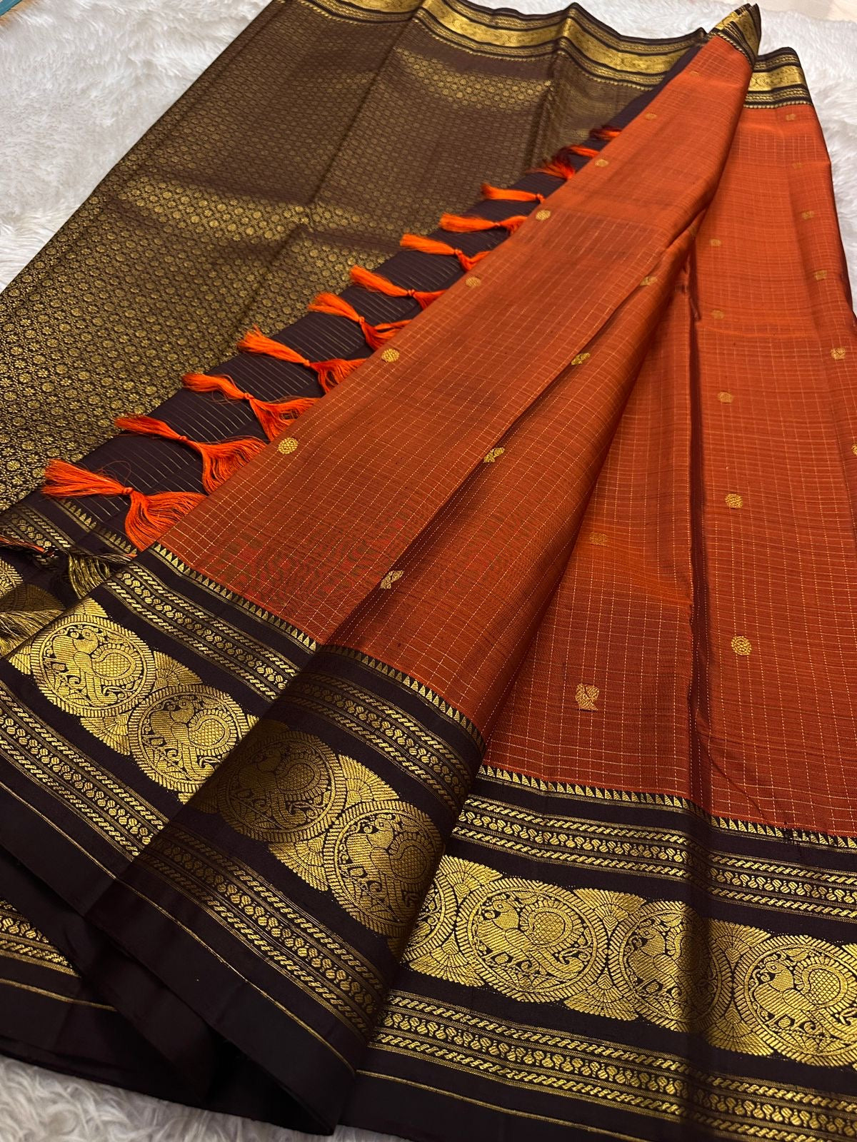 Diya Rust Orange – Pure Silk Kanchipuram
Rust-orange kattam checks with coin buttas ✨
Coffee-brown korvai borders with grand Annam medallions 🪔
Rich coffee-brown brocade pallu with zari stripe weave 🌿
Silk Mark Certified • Ships in Two Weeks • Free Ship