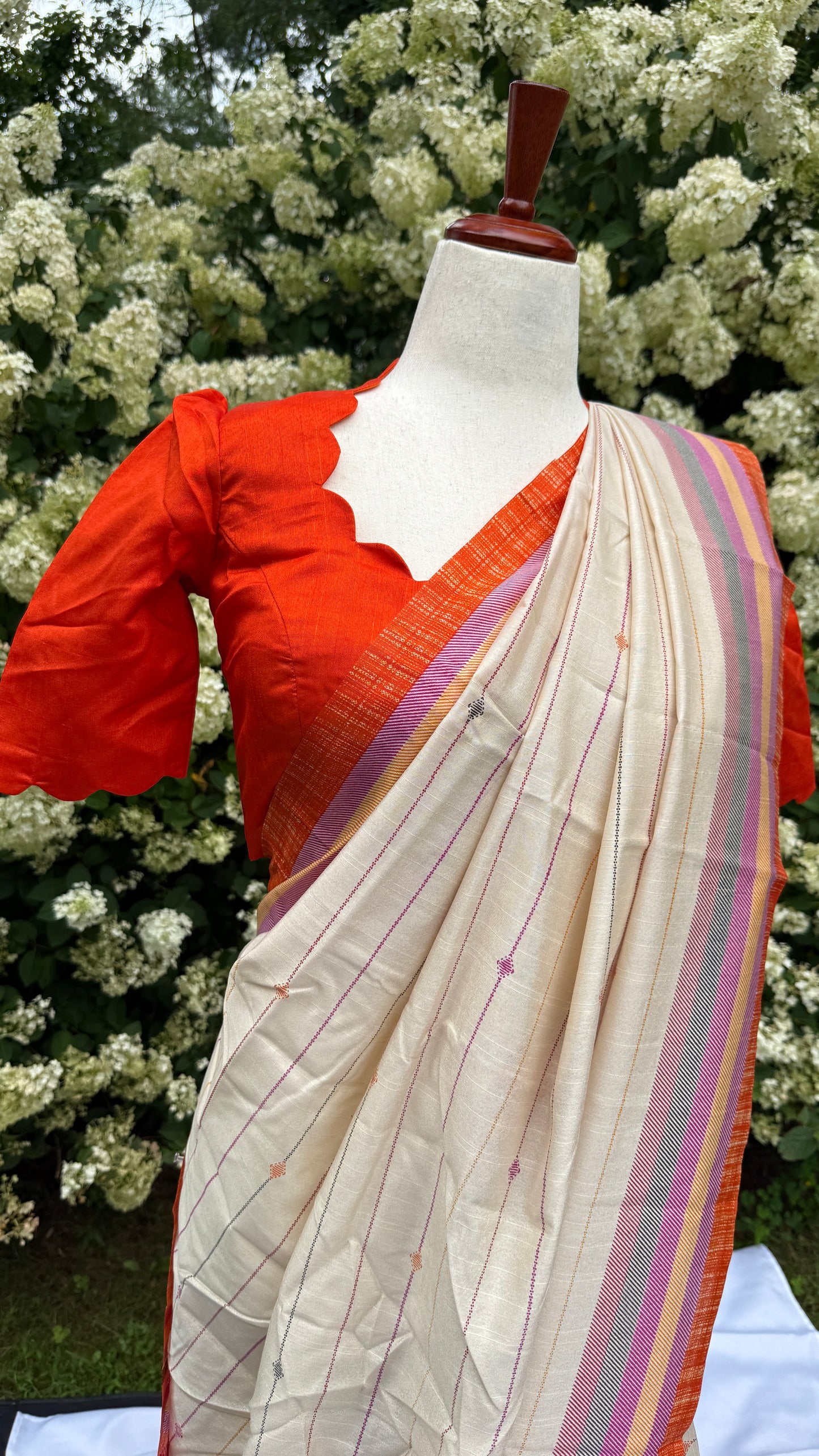 Tamara – Ivory Cream Semi-Silk Saree with Vibrant Orange Border
Paired with a Scallop Neck & Sleeve Ready-to-Wear Orange Blouse (Size 36–42)