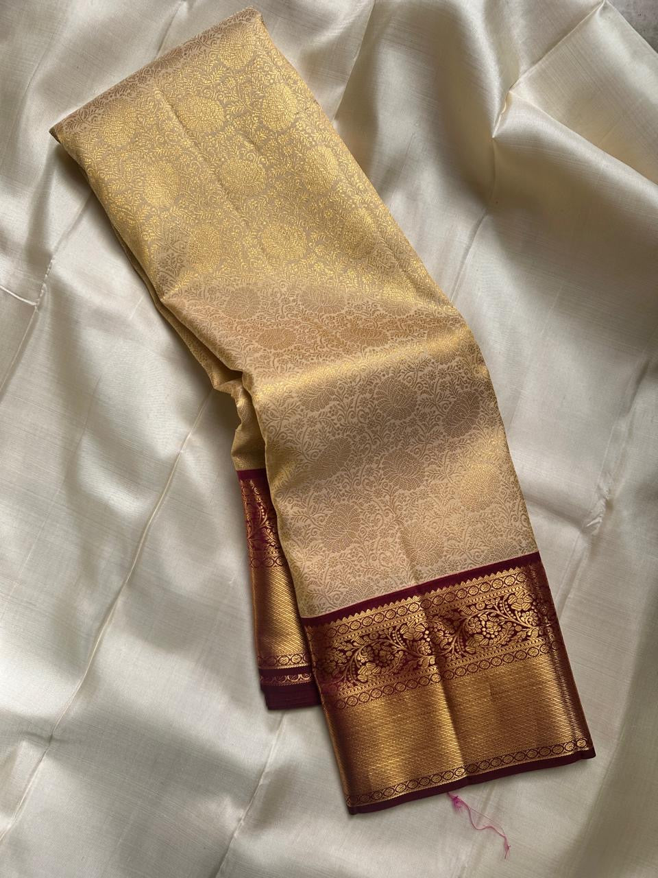 Ragini – Ivory & Gold Kanchipuram Pure Silk Saree with Floral Jaal & Maroon Baavanji Border
Timeless elegance shines through the delicate ivory base and shimmering gold zari floral jaal. The rich maroon Baavanji border and intricate pallu details complete