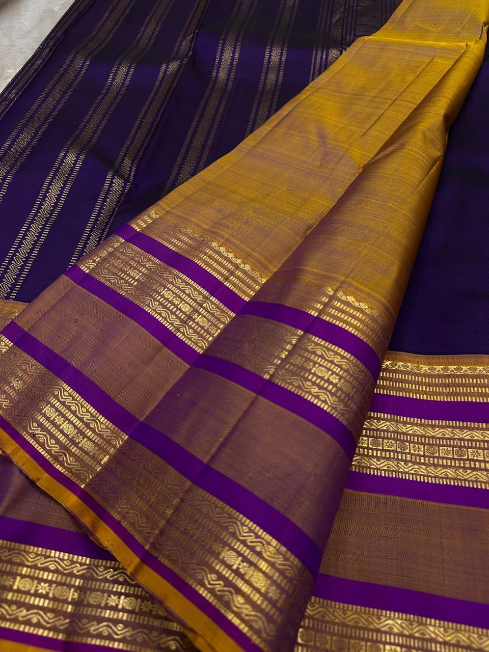 Swarna Laya — Pure Silk Kanchipuram Saree
Deep vaadamalli purple with gold zari buttas, antique-gold border, and rich striped pallu.
Silk Mark Certified • Free USA Shipping • Ships in Two Weeks.