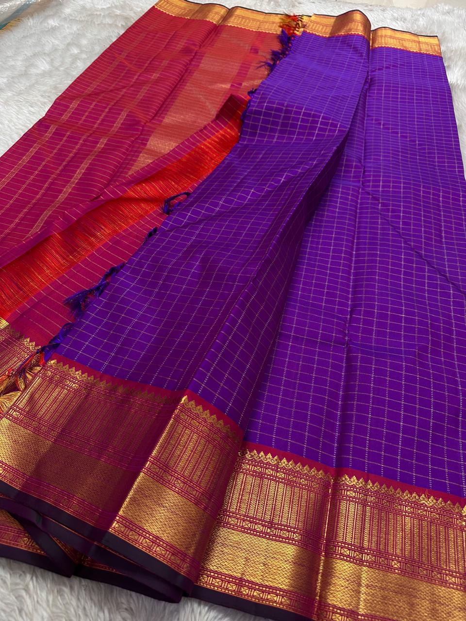 Amethyst Zari Kattam – Pure Kanchipuram Silk Saree
Rich Amethyst Purple Body with Golden Zari Checks
Broad Gold Zari Border with Red Highlights & Temple Motifs
Radiant Ruby Red-Orange Pallu with Lustrous Zari Stripes
Silk Mark Certified, delivery in 2 we