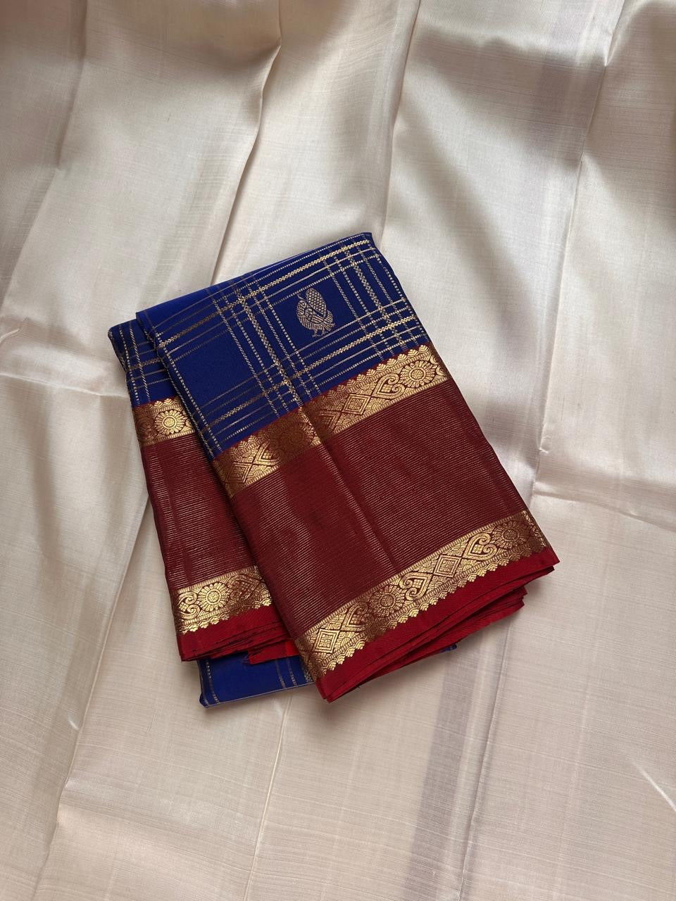 Sapphire Ruby Kattam – Pure Kanchipuram Silk Saree
sapphire blue body with gold kattam checks & buttas
Contrast ruby-red korvai borders with intricate gold zari weave
Grand ruby-red pallu with floral motifs
Silk Mark Certified | ships in 2 weeks