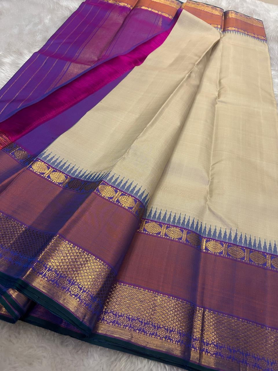 Vaidhehi – Ivory Kanchipuram Silk Saree
A classic ivory silk saree with a shot purple-orange Rudraksham border and a rich Thazhampoo reku pallu—timeless elegance woven with tradition