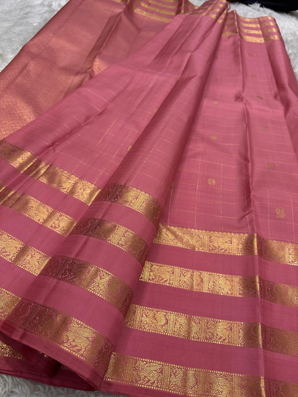 vasantham pink – Handwoven Kanchipuram Silk Saree
A poem in pink silk. The body glows in a serene rose pink, softly accented by delicate gold vertical lines and dainty gold zari buttas that glint like little blessings.