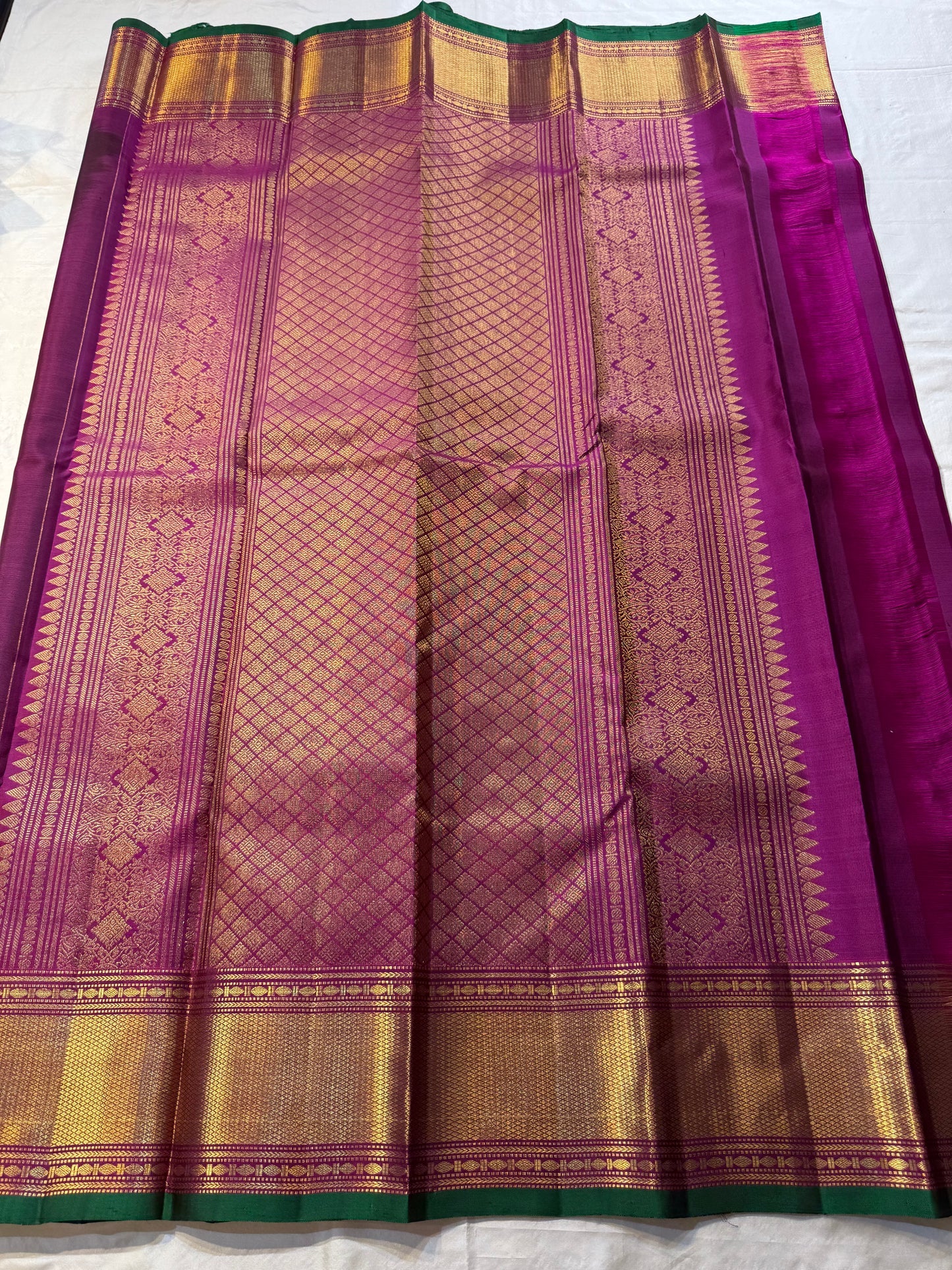 Plum & Magenta Round Butta – Pure Kanchipuram Silk Saree
Deep plum body with bold round gold zari buttas
Contrast green selvedge & gold tissue borders with magenta detailing
Grand magenta-pink pallu with full zari diamond jaal & geometric panels
Silk Mark