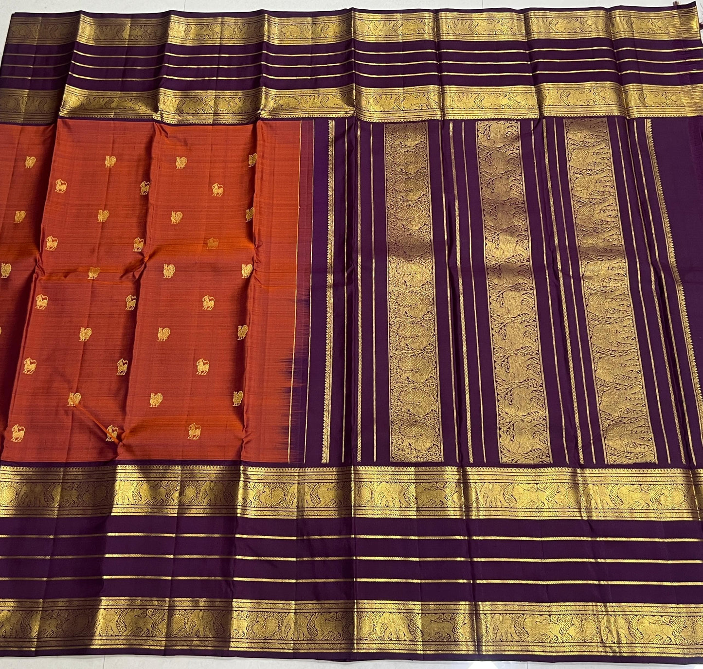 Karpagam – Burnt Orange & Coffee Elegance ✨🪔
A glowing burnt orange body adorned with gold zari peacocks 🦚 and mythical Yazhi 🐉 motifs. The deep coffee border shimmers with Varisaipet geometric zari, while the grand pallu unfolds in panels of Vanasring