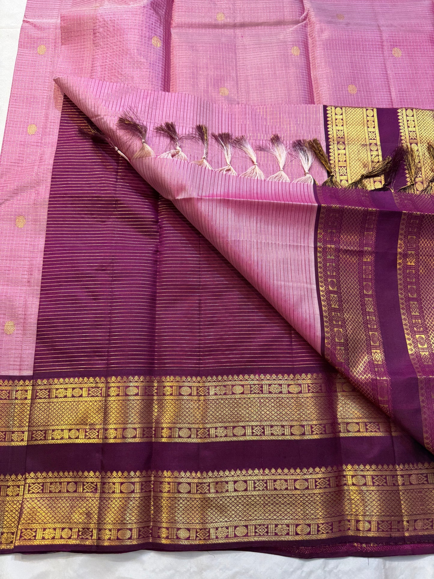 Rose Mist Zari Kattam — Kanchipuram Pure Silk
Blush rose-pink body with micro kattam (checks) in zari & scattered soorya-chakram buttas
Contrast mulberry purple korvai borders with rich gold zari detailing
Free shipping within USA silk mark certified