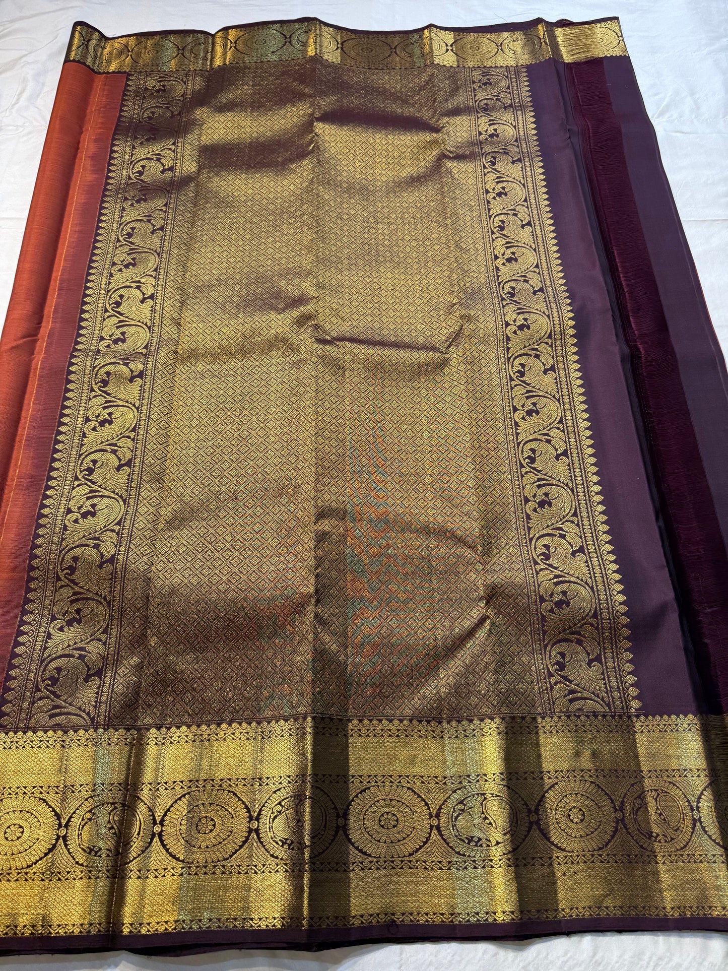 Rust Orange Supreme – Korvai Kanchipuram Pure Silk Saree
Shot rust-orange body with gold chakram & mankolam buttas all over
Deep purple korvai border with annam & chakram zari medallions
Rich vadamalli zari-brocade pallu | Contrast blouse | Fall & Pico Do